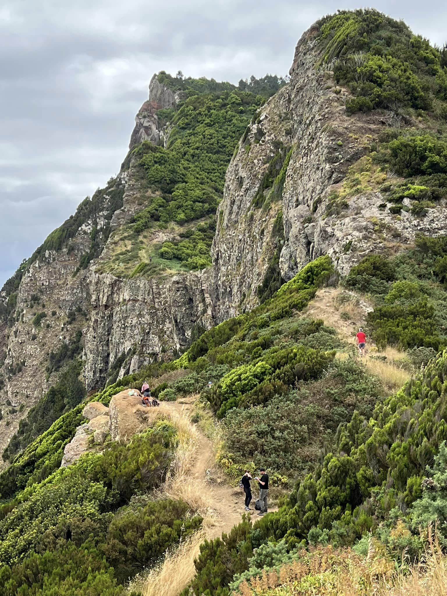 large rocks on green mountain with cloudy skies