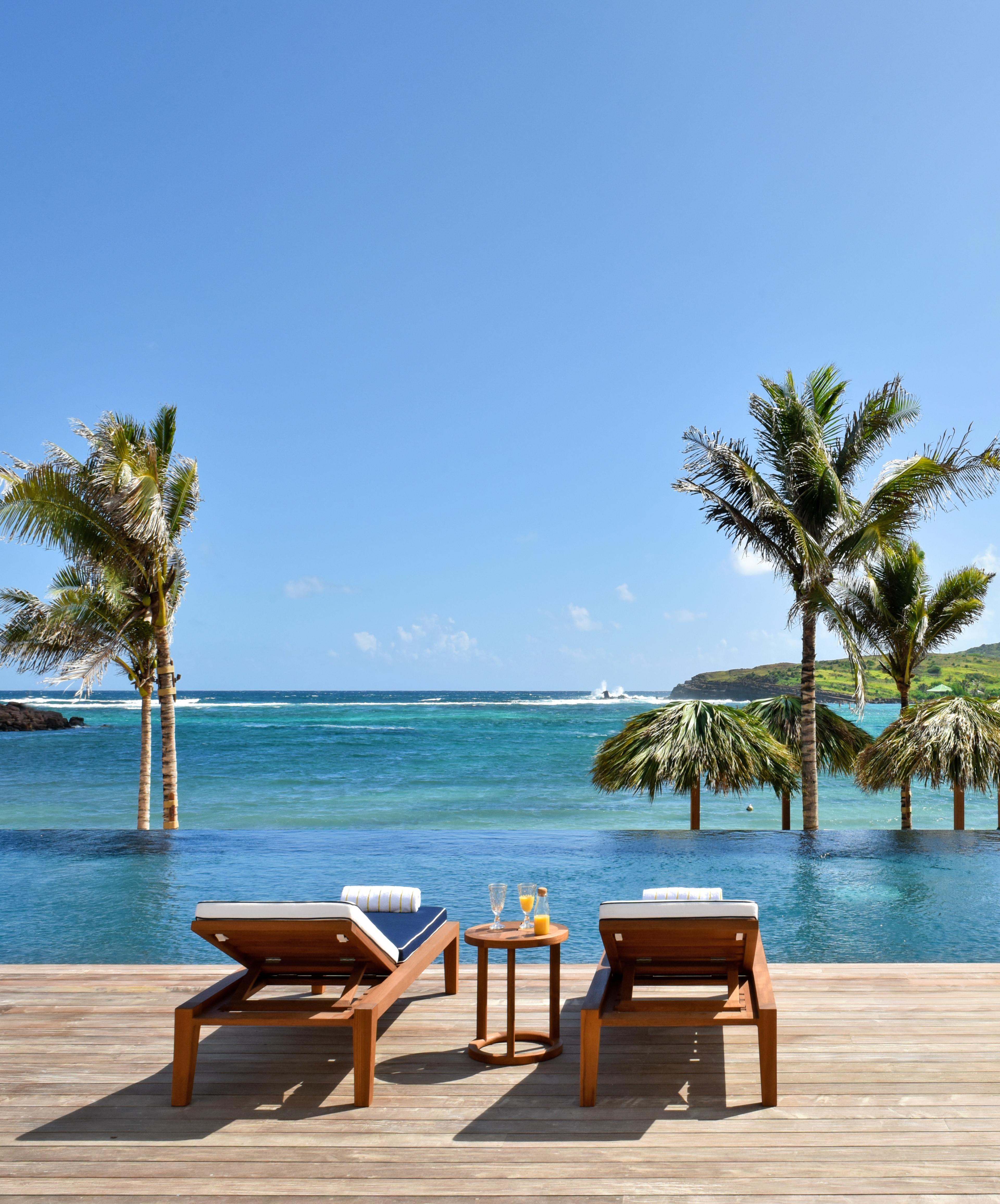 lounge chairs and palm trees next to the ocean during daytime