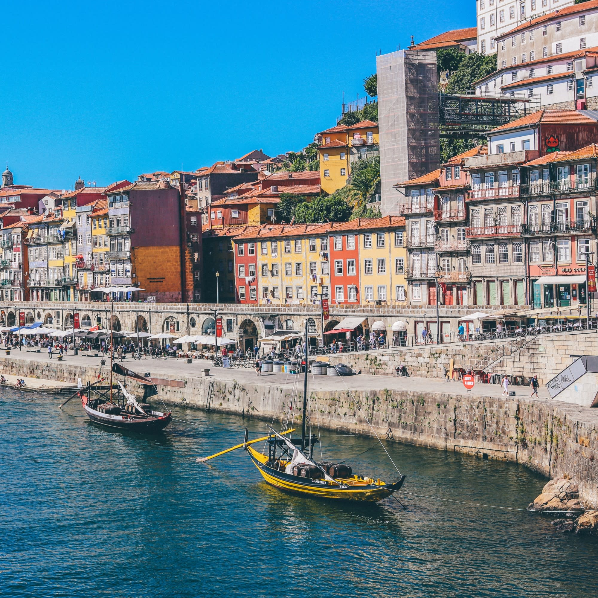 Colorful buildings in front of a river with sailing boats.