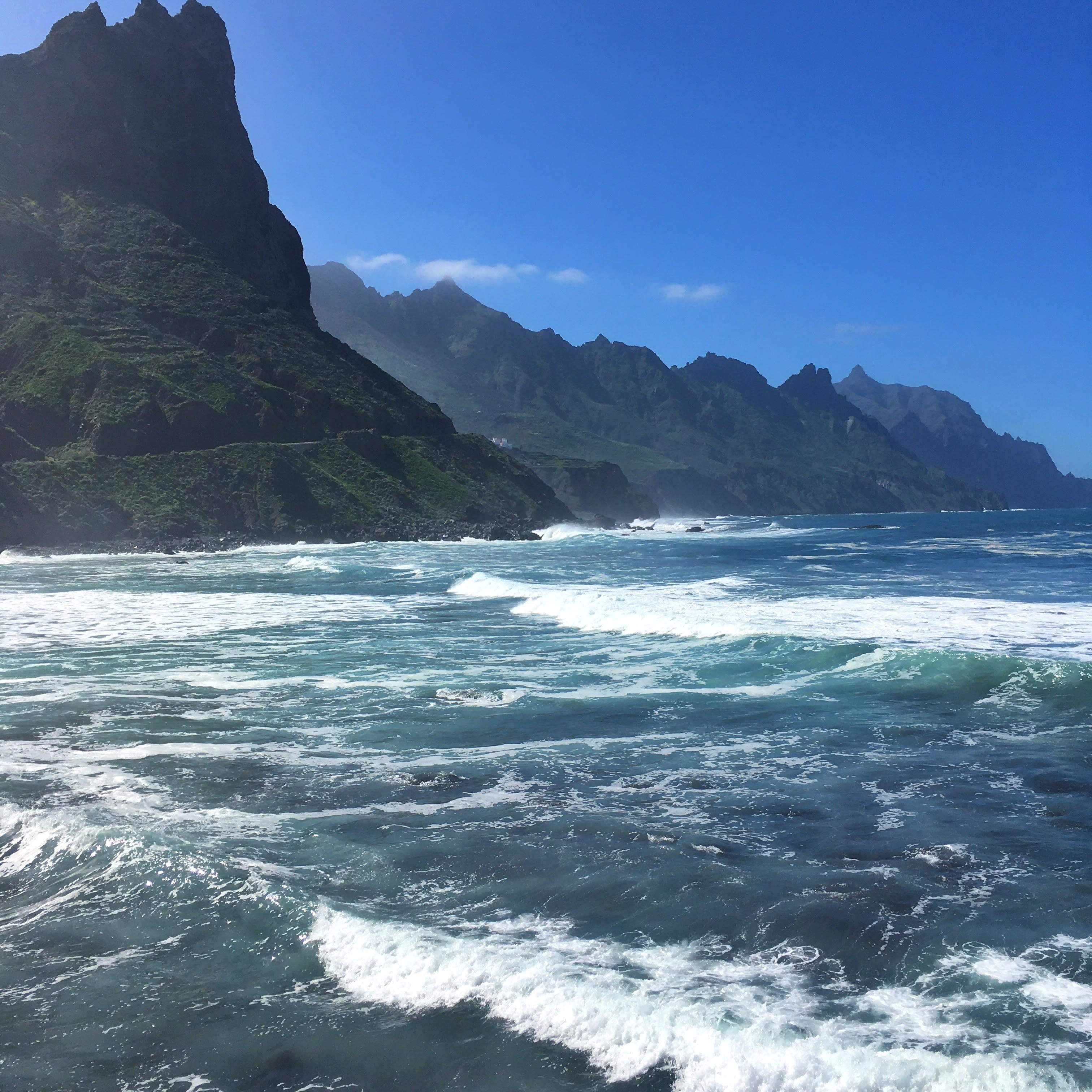 A sea with blue water and mountains at the back.