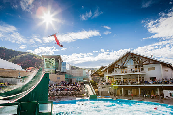 Utah Olympic Park with clear skies, the sun shining and people in the stands.