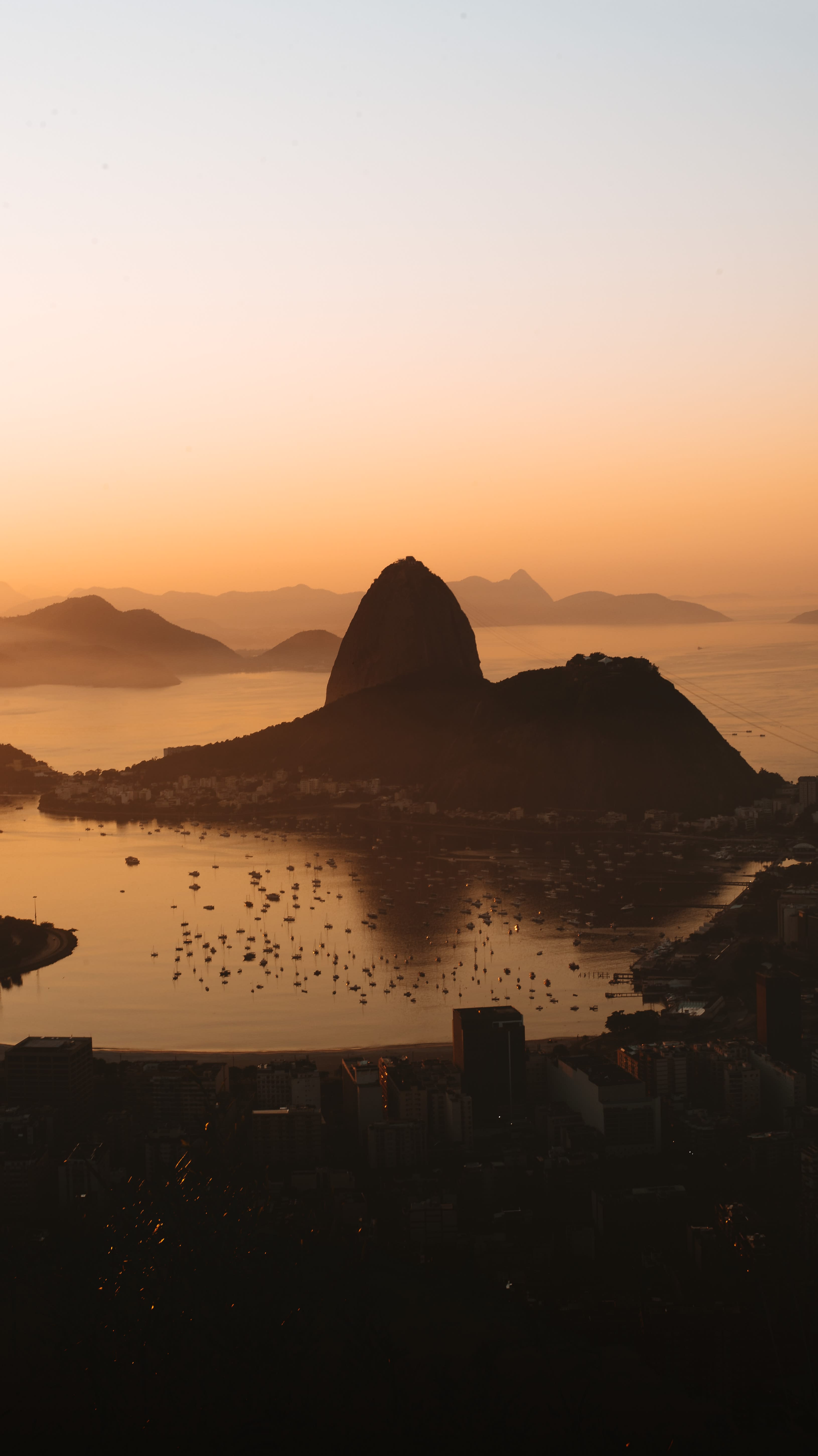 sunrise over calm waters and silhouettes of mountains