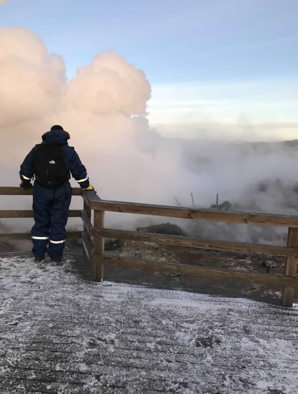 A person overlooking the smoke near a wooden fence outside.