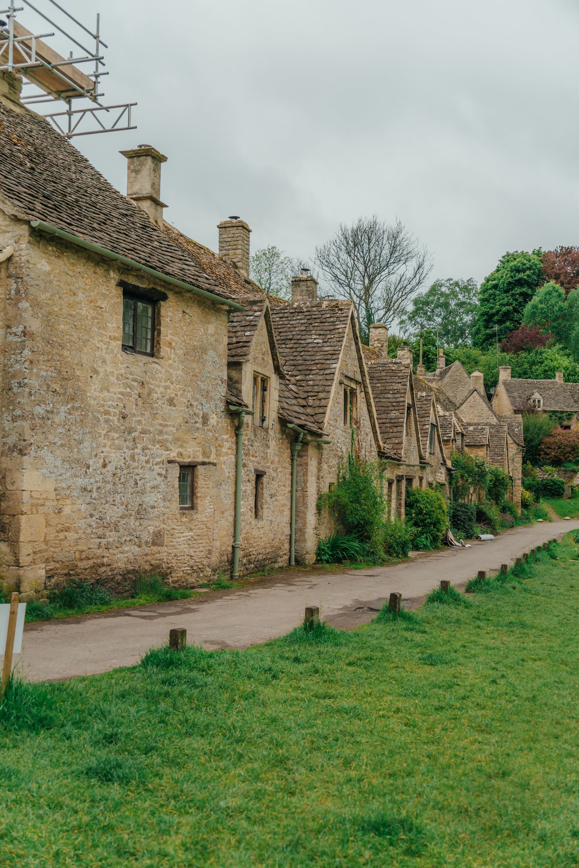 A row of old brown houses on a grassy field.