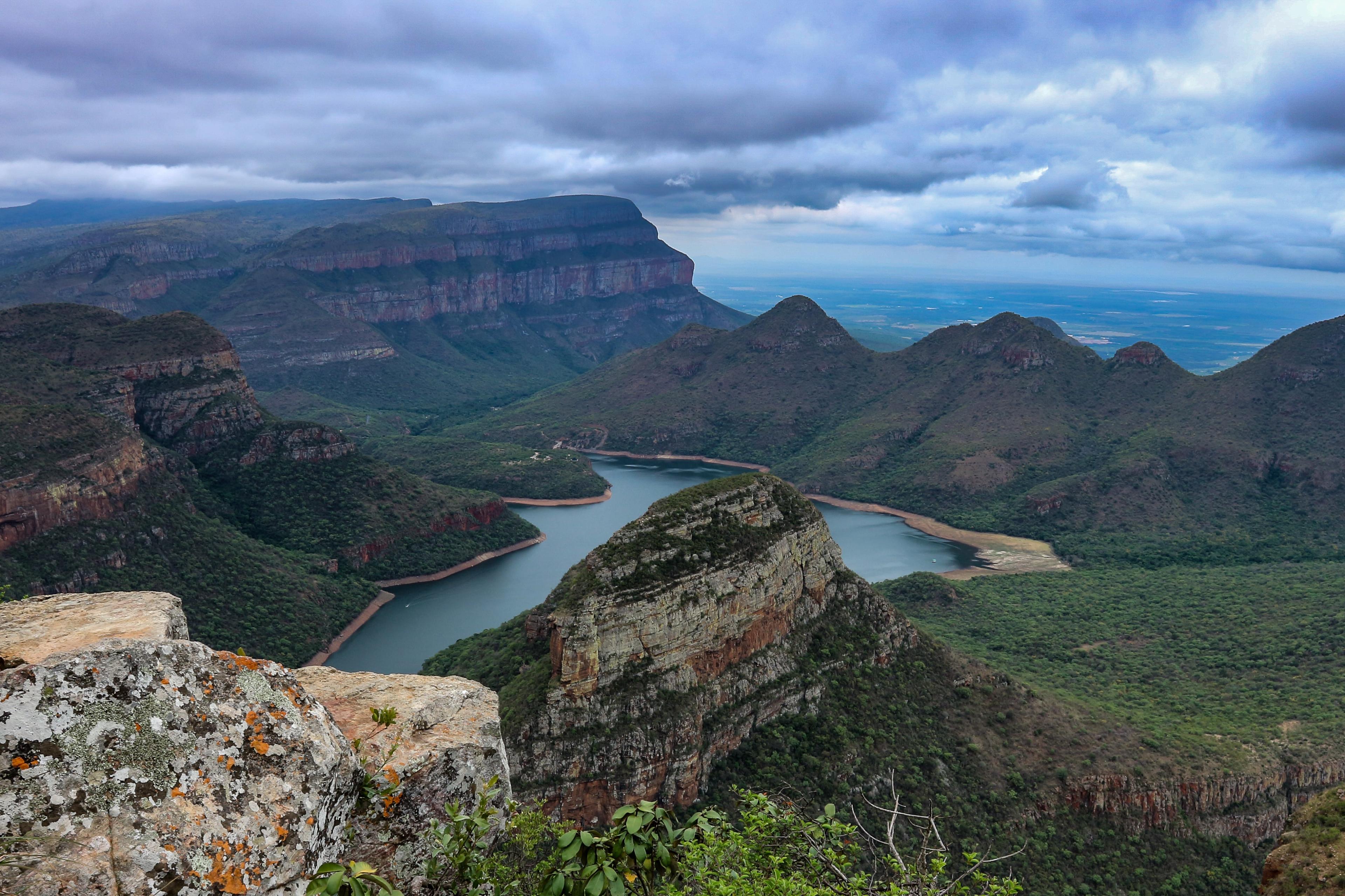 Body of water surrounded by mountains with clouds in the sky during daytime