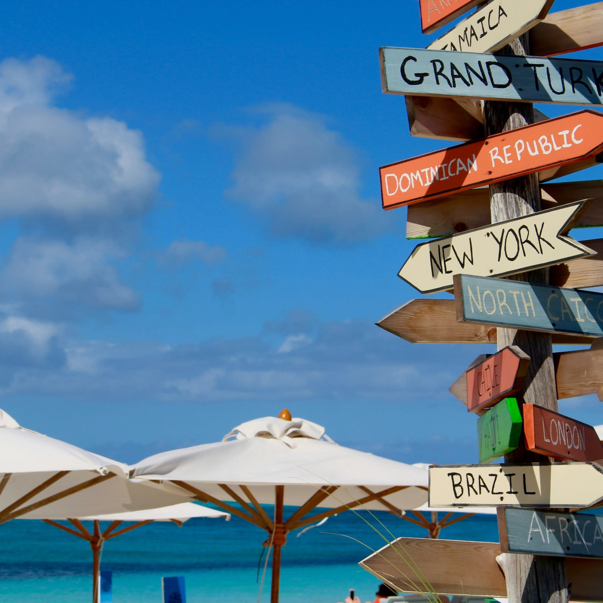 Beach with umbrellas and sign board.