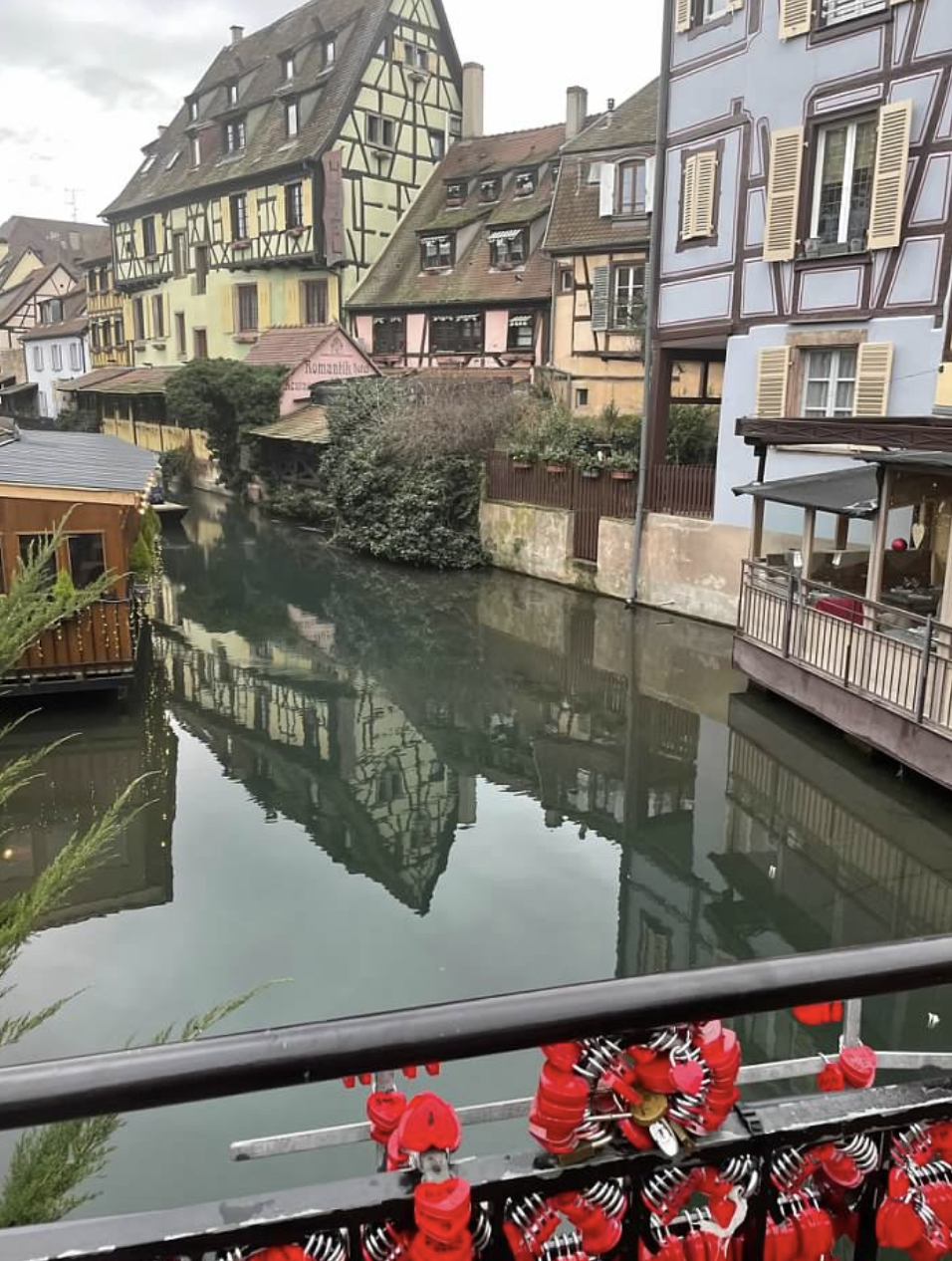 A bridge on a canal with locks on it, surrounded by colorful timber buildings.
