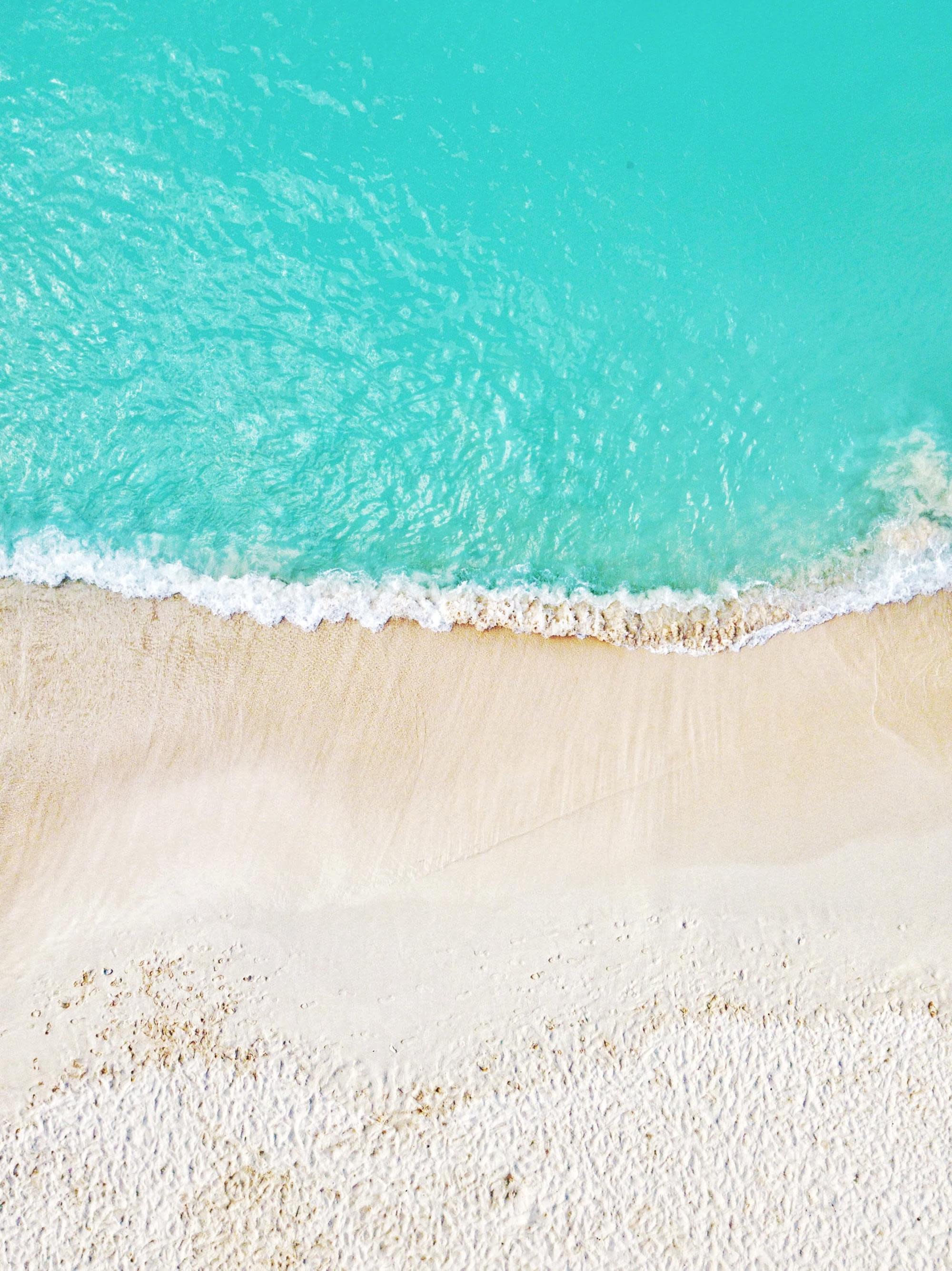 aerial view of pristine blue water and white sand beach
