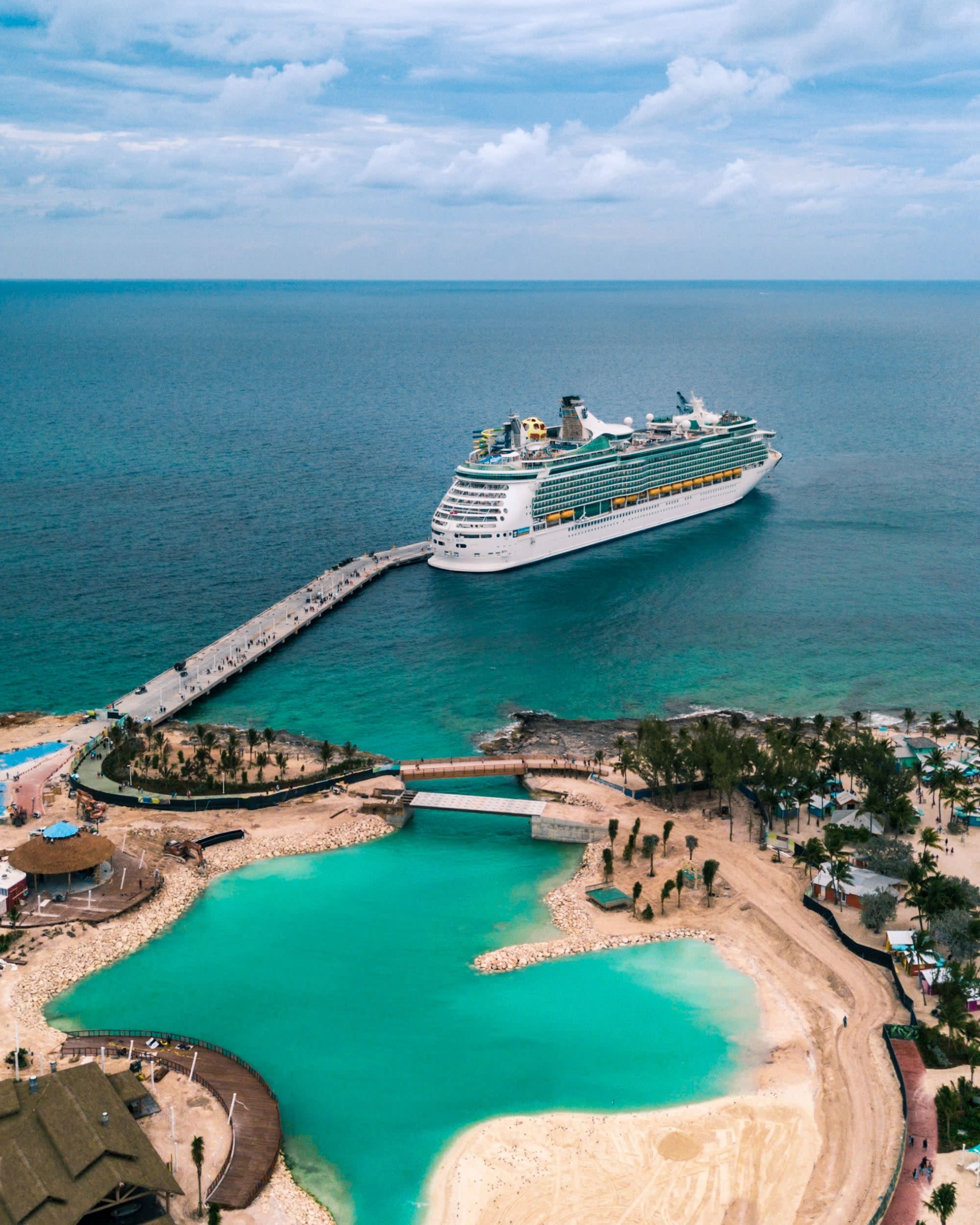 An aerial view of a white colored cruise ship on the water near an island.
