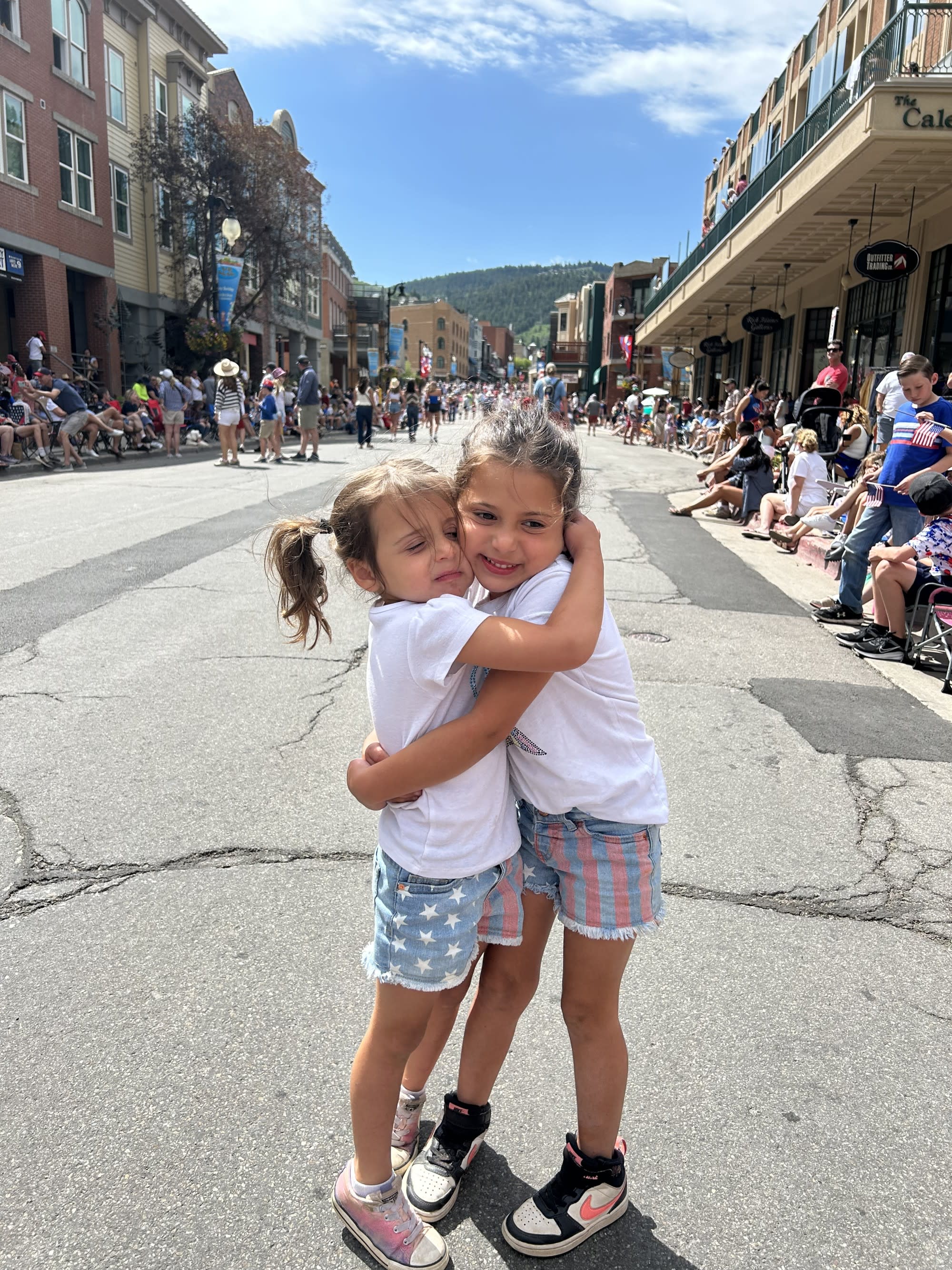 Two kids hugging each other on a street.