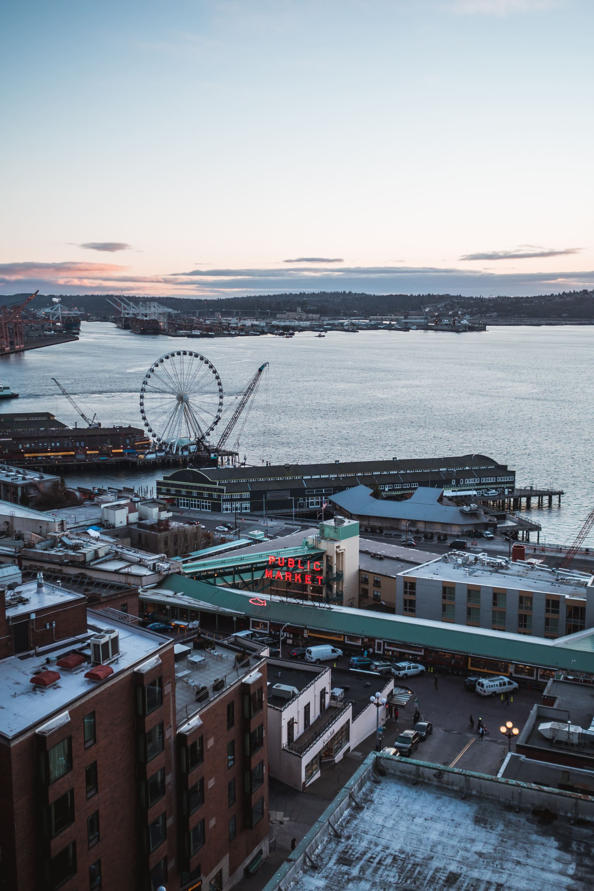 a winter city on the water at sunrise with a ferris wheel