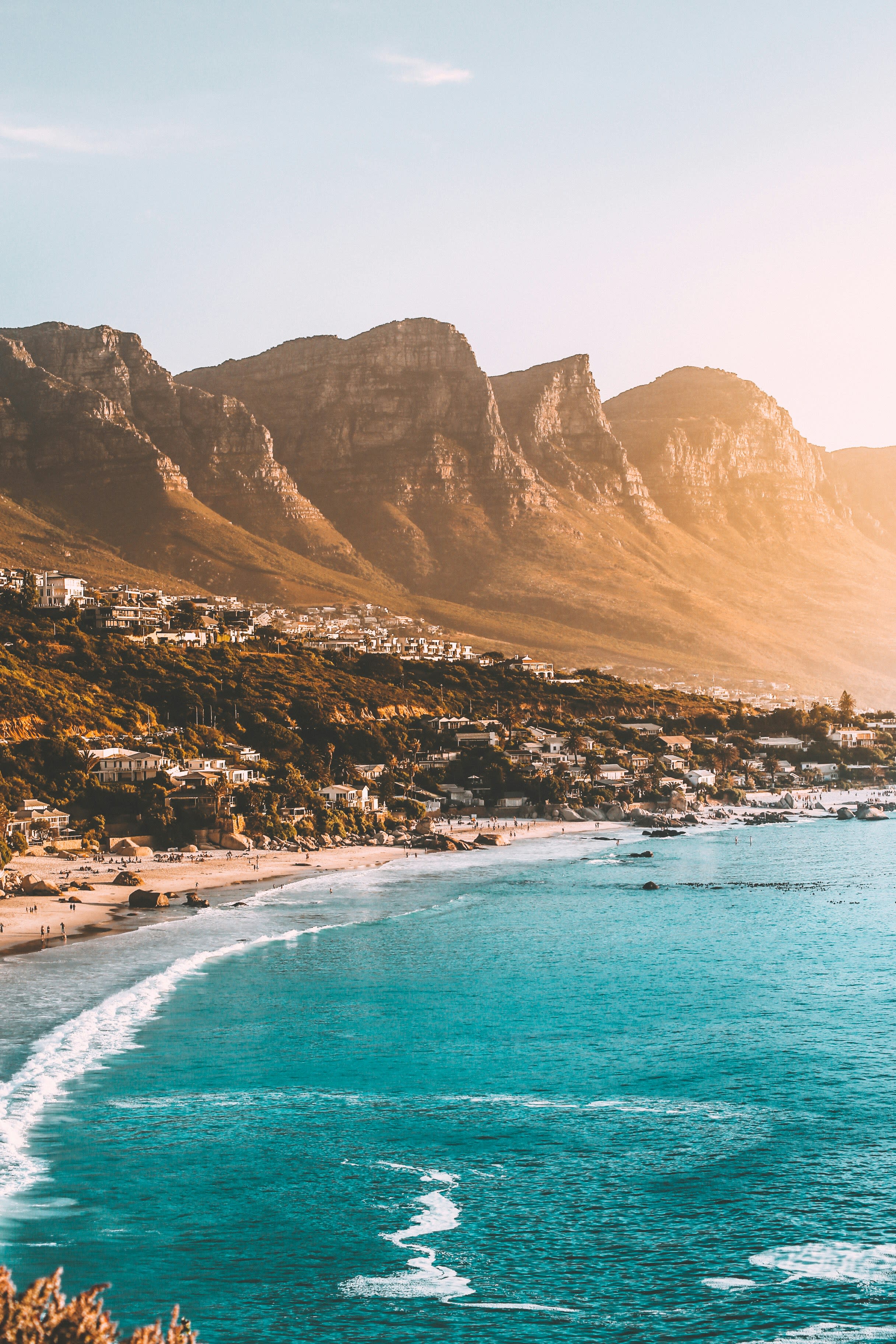 A beach shore in front of tall cliffs during the daytime