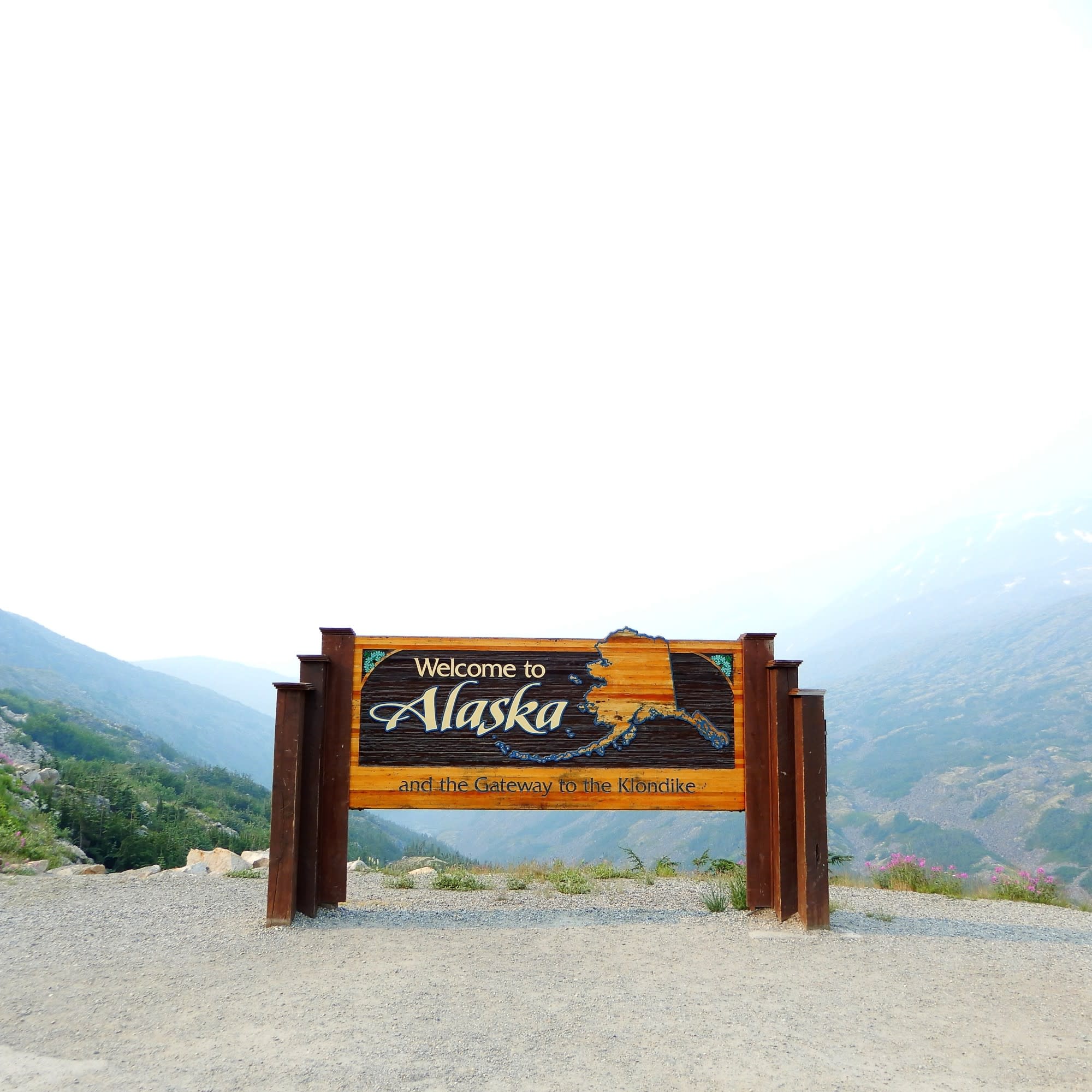 A welcome signage on gray sand during daytime.