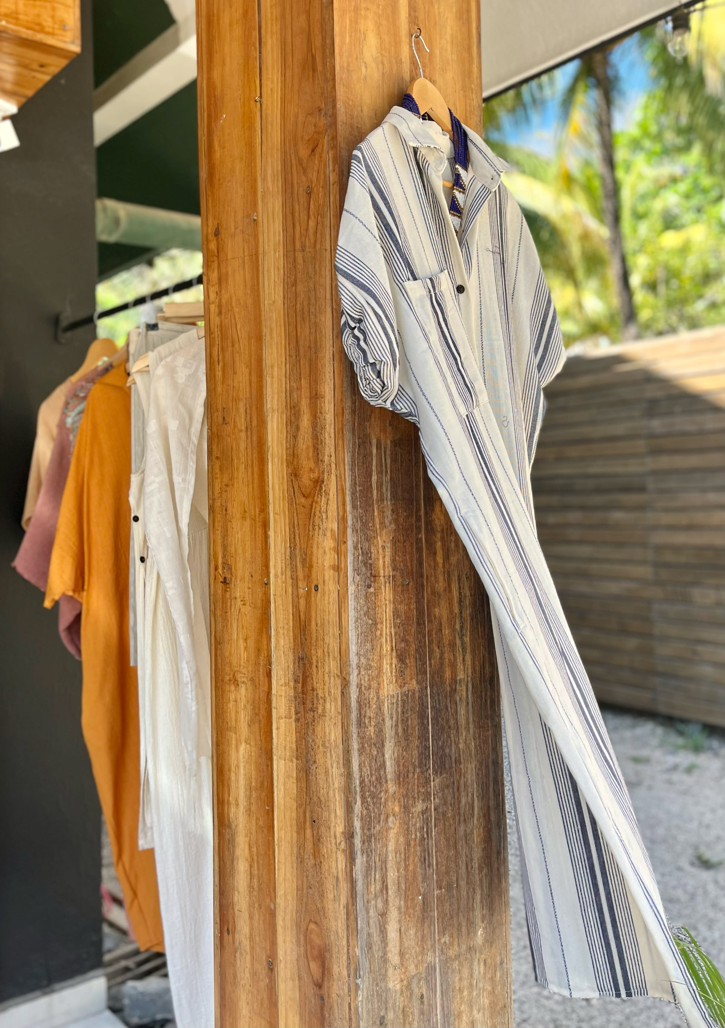 Assorted brightly colored luxury clothing hanging outside of the store.