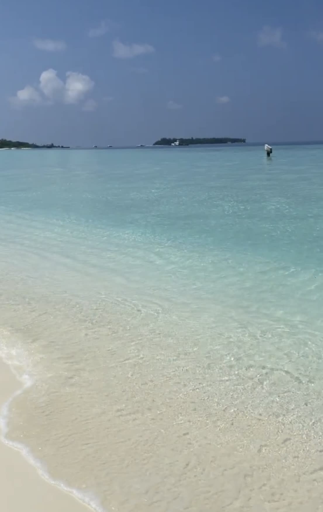 A view of crystal clear blue water against the white sandy beach.