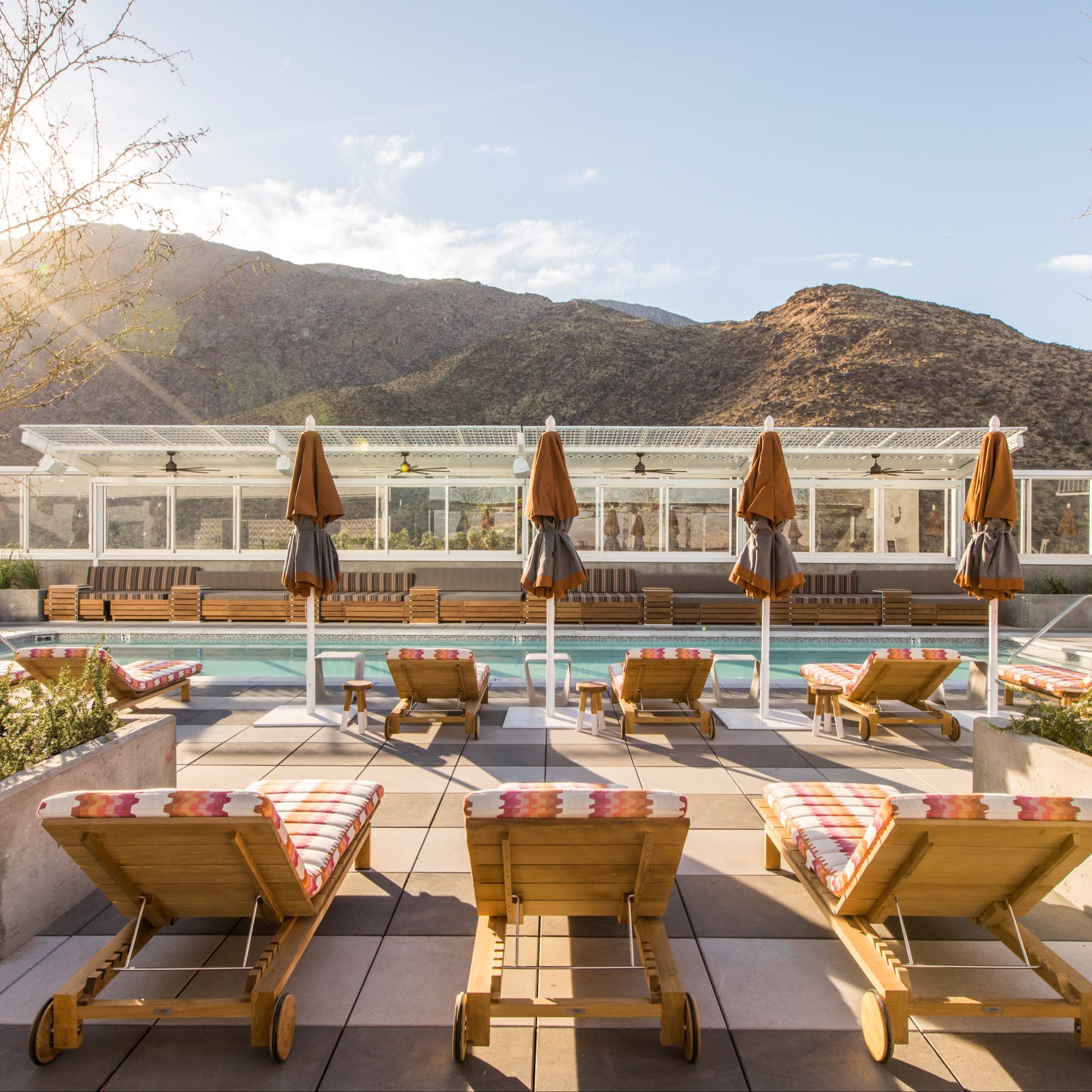 Pool with pool chairs and mountains at the back.