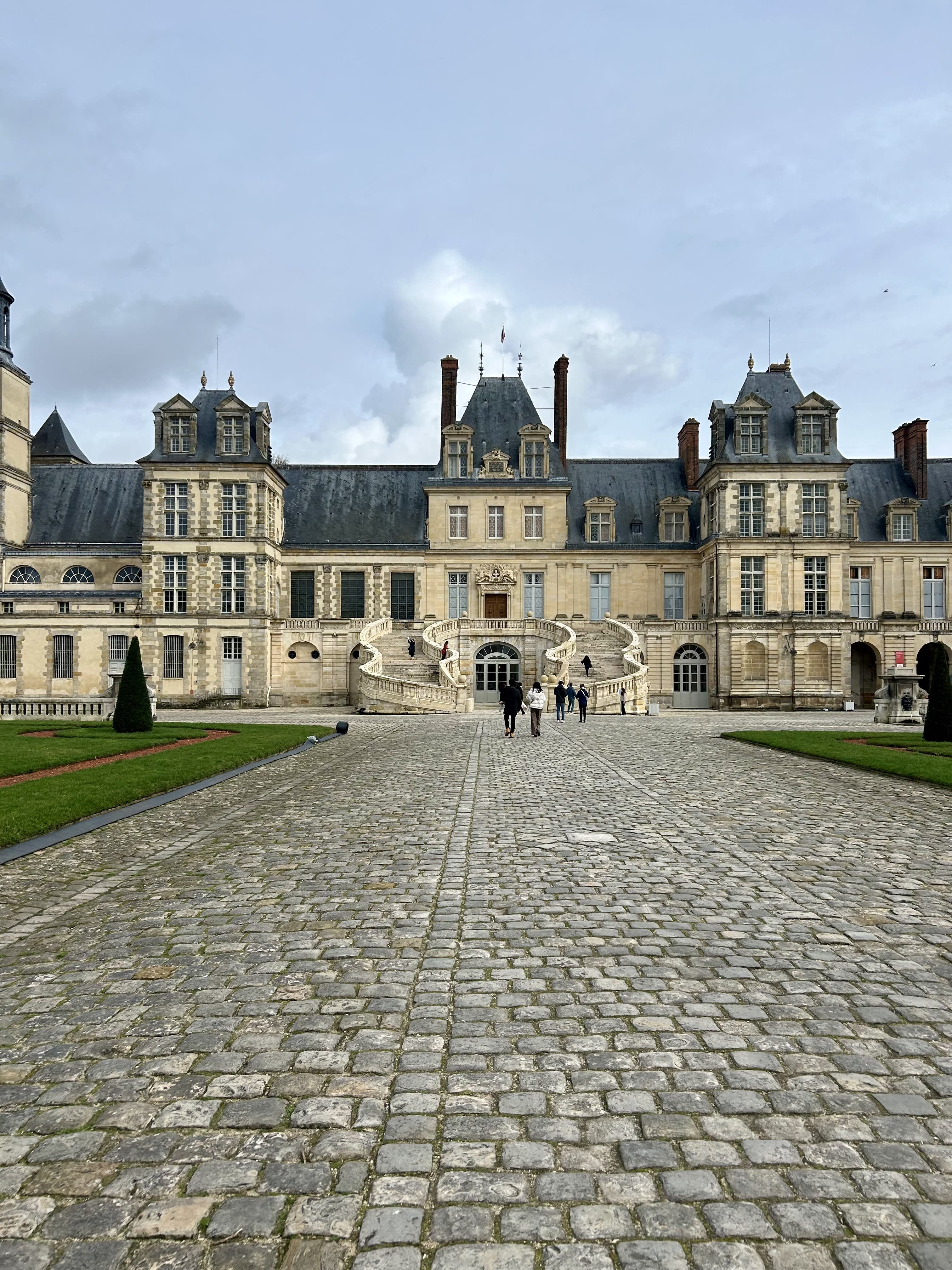 A brick pathway leading to a large castle during the daytime