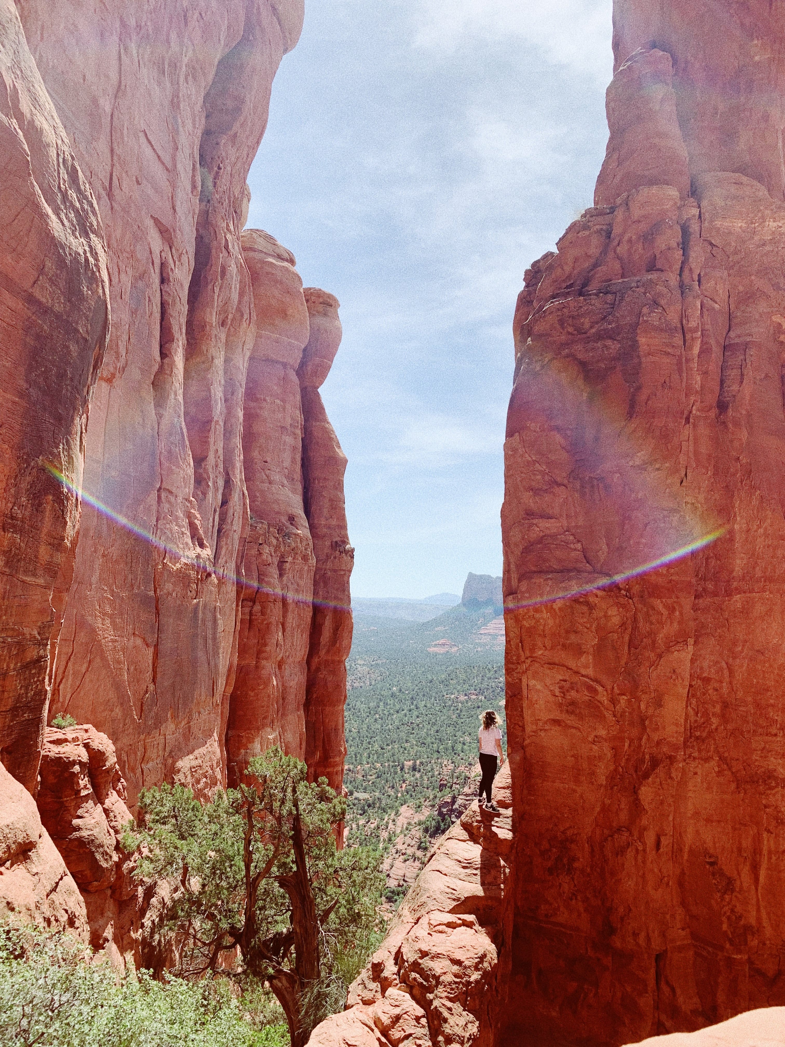 Person standing on cliff with blue skies during daytime