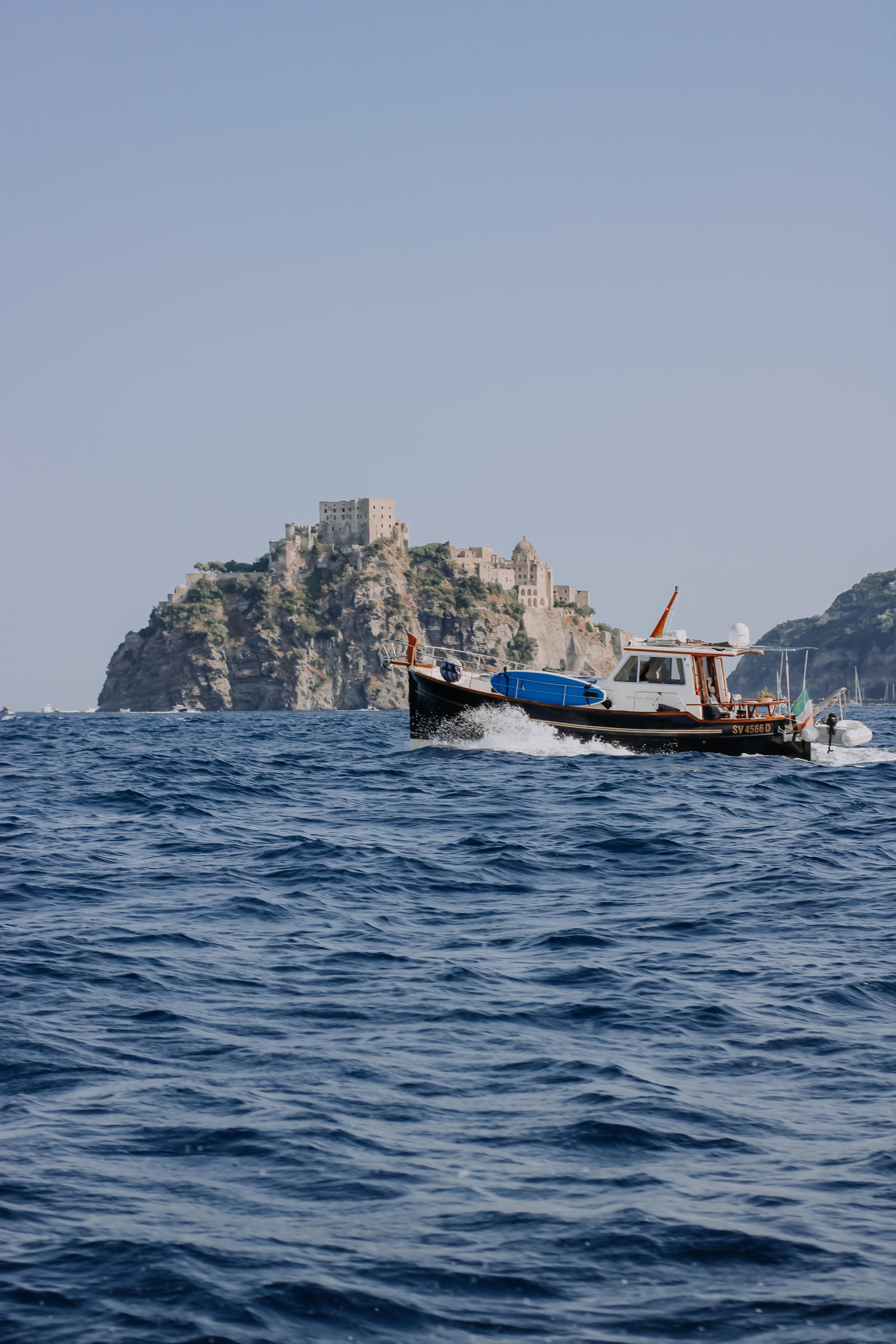 Boat on the water in front of Castello Aragonese in Ischia, Italy