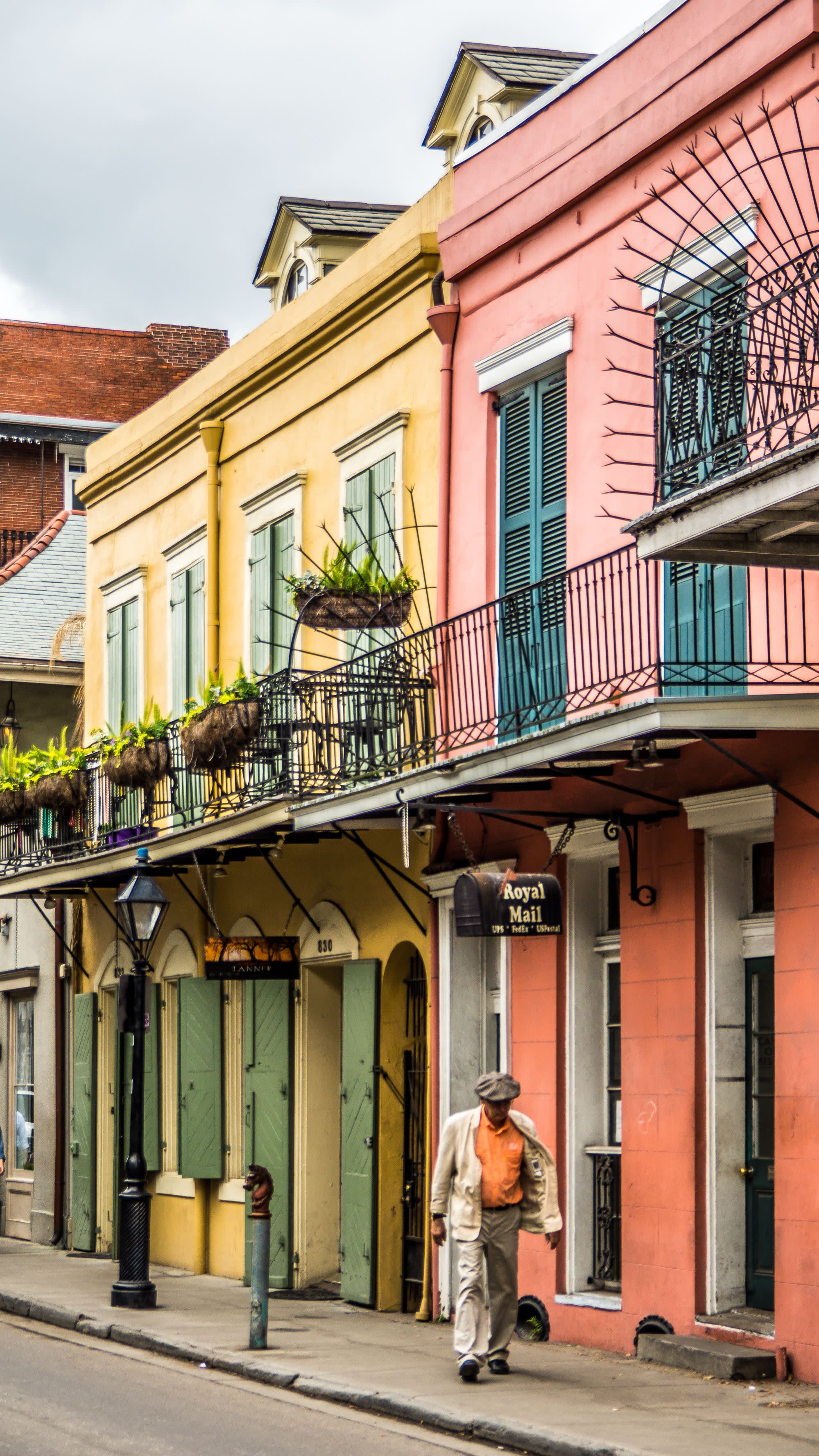 Pink and yellow buildings with a man walking on a side walk.