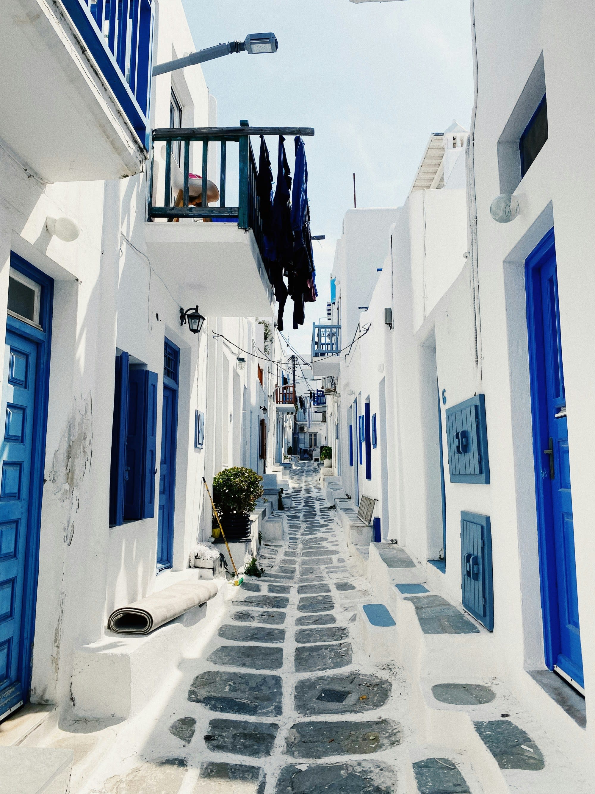 Street between white buildings and blue doors on a sunny day.