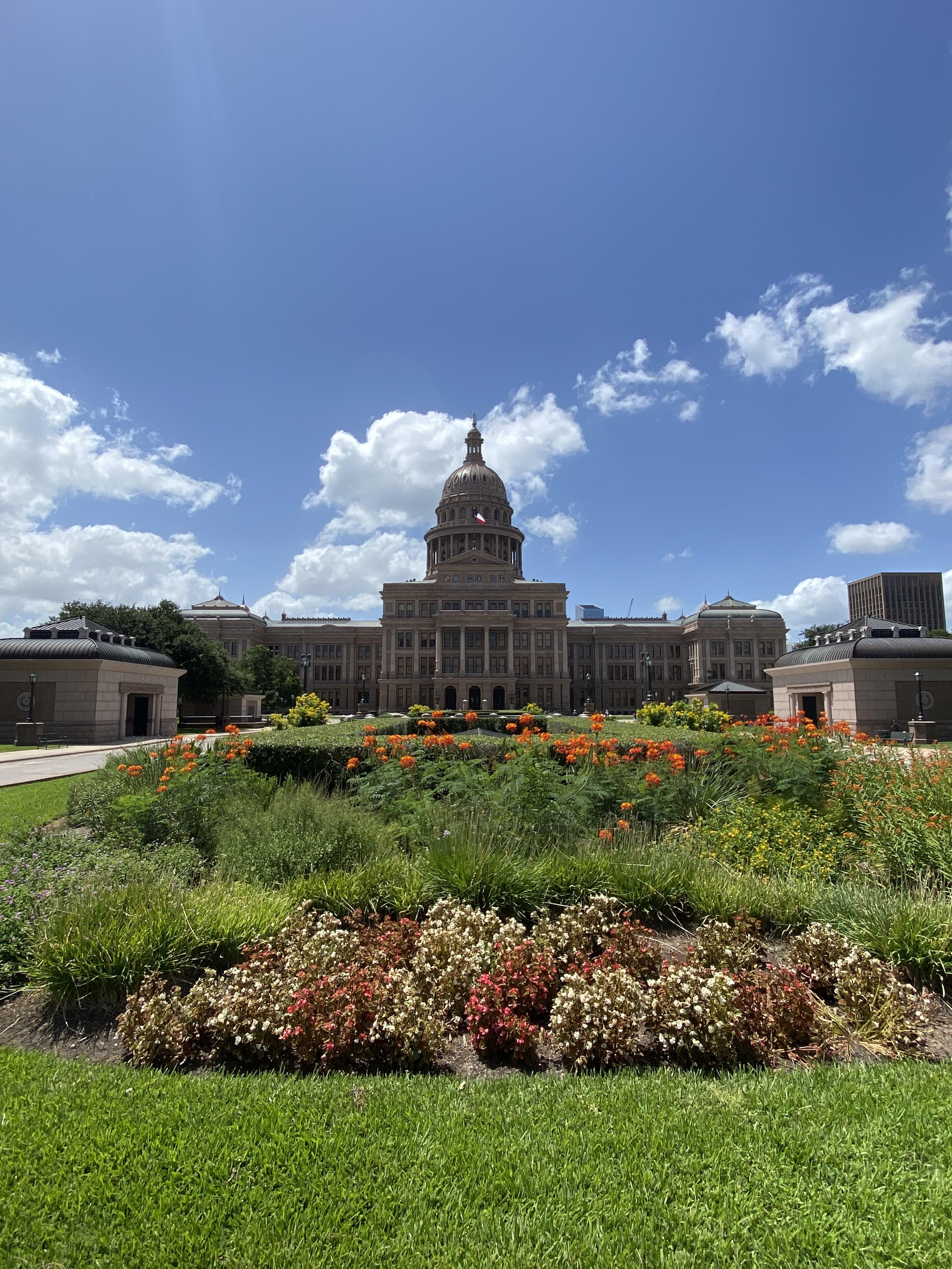 The Texas State Capitol at Austin, Texas reaches to the sky on sunny day dotted with clouds.