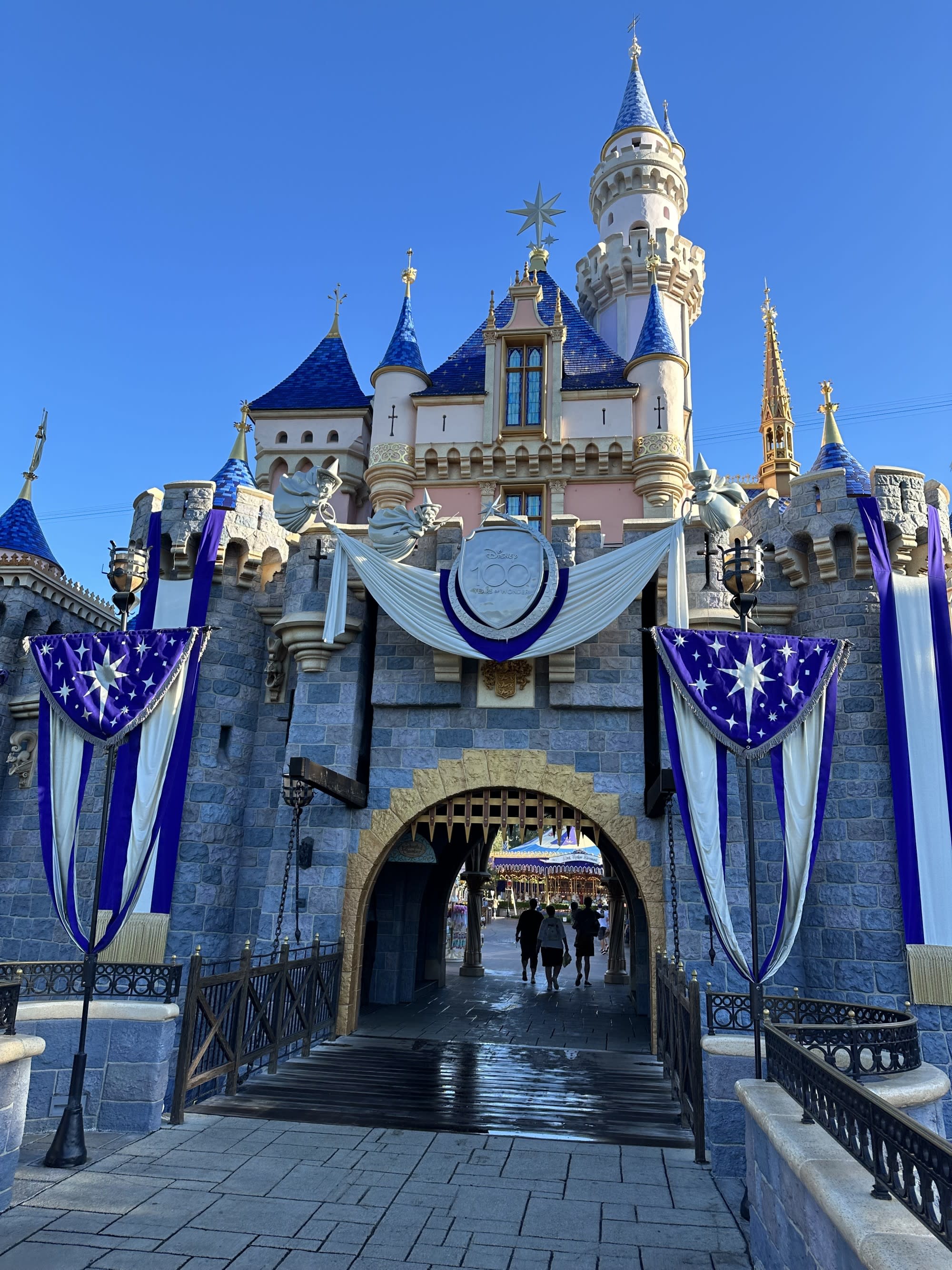 A castle with blue and gold turrets, adorned with star-spangled banners, under a clear blue sky.