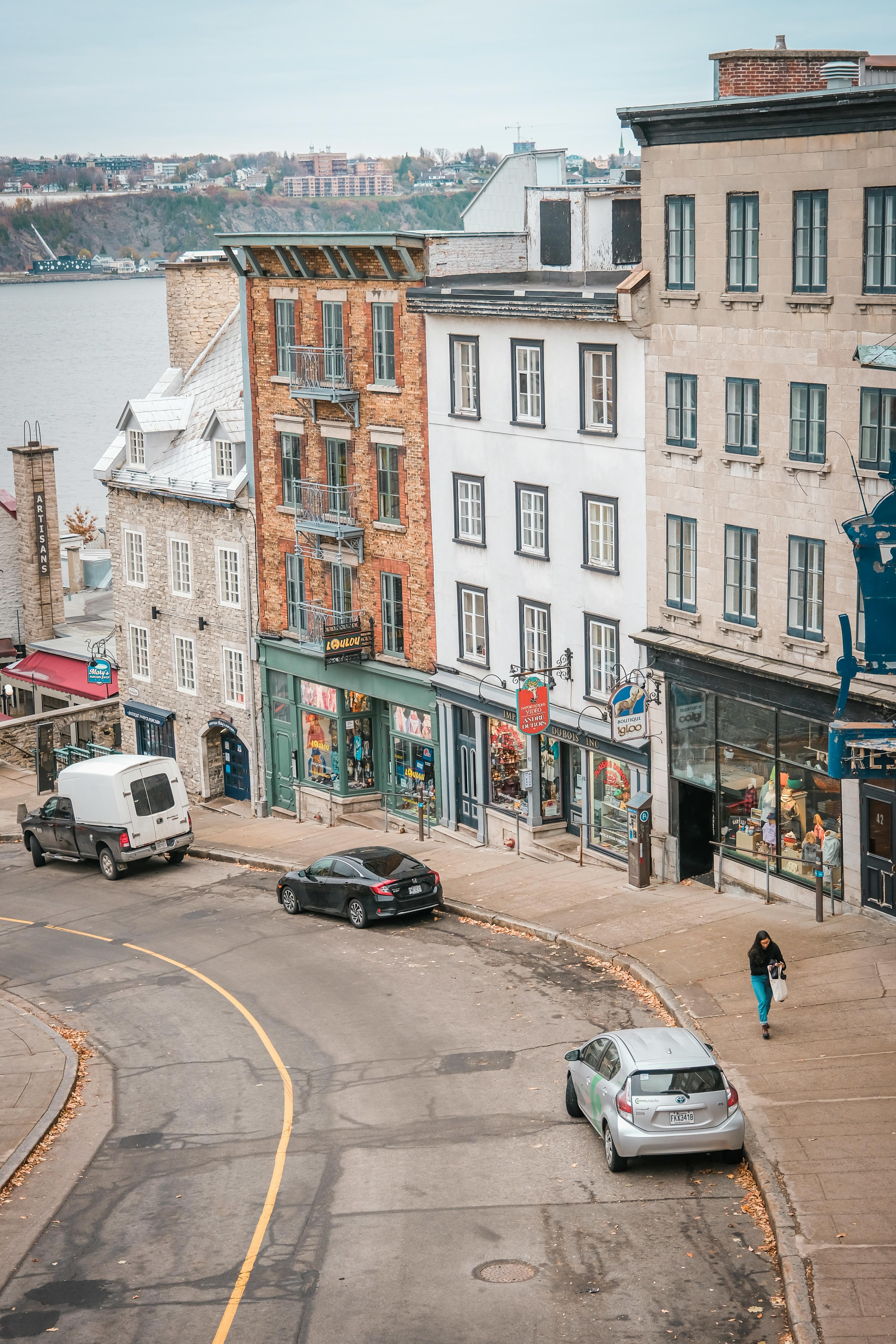 A view of a downward sloped street in Old Quebec with quaint buildings and stores.