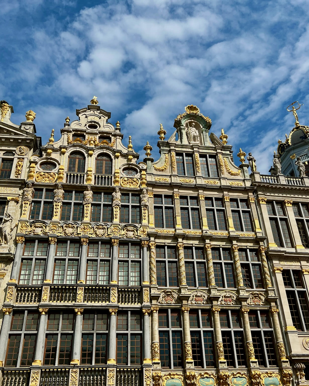 The architecture of Grand Palace stunningly reaches to the sky on a clear day dotted with clouds.