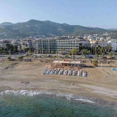 Aerial view of the resort beach as the waves lap the shore on a sunny day.
