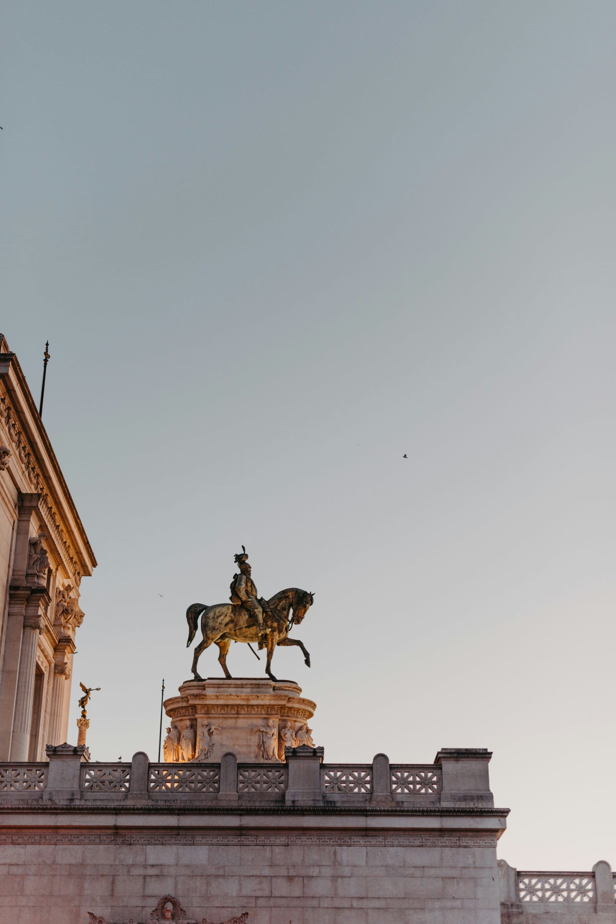The image presents a majestic equestrian statue, silhouetted against the serene backdrop of a dawn or dusk sky, part of a Tuscany day trip from Rome.