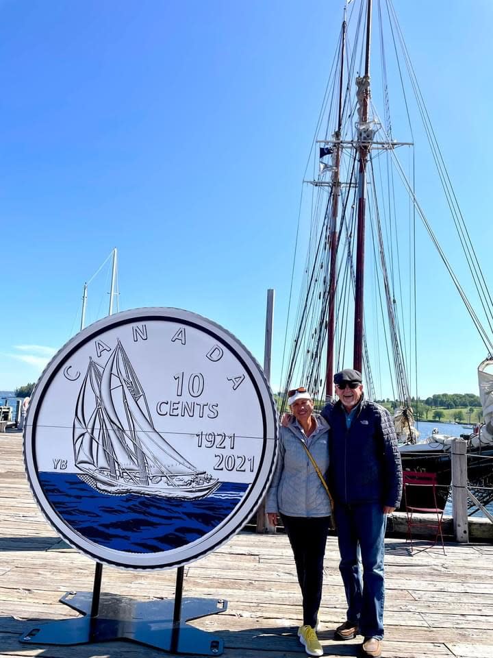 Diana and a man standing next to a giant Canadian dime in front of boats in the harbor