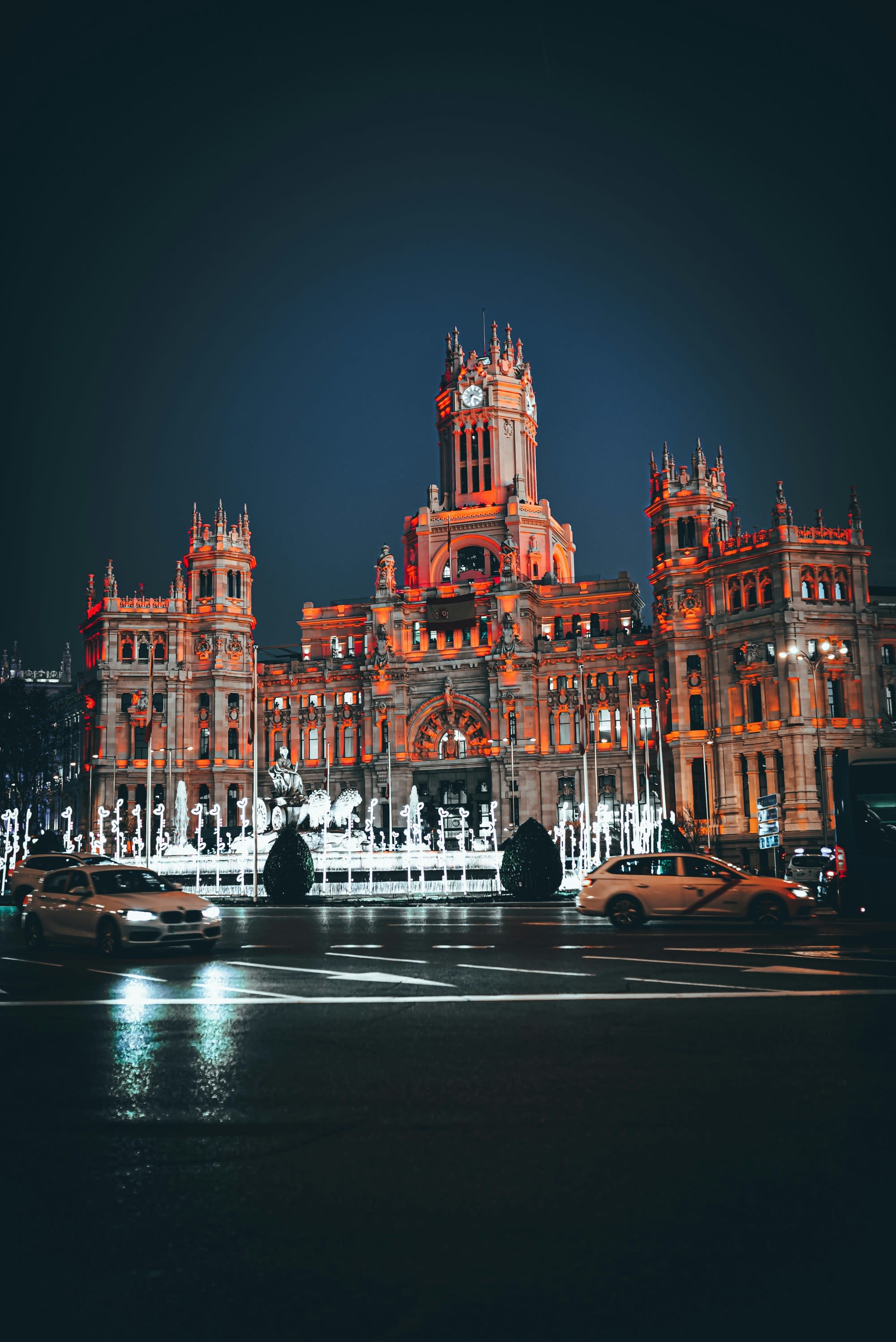 A grand building bathed in night lights presents a striking red summit