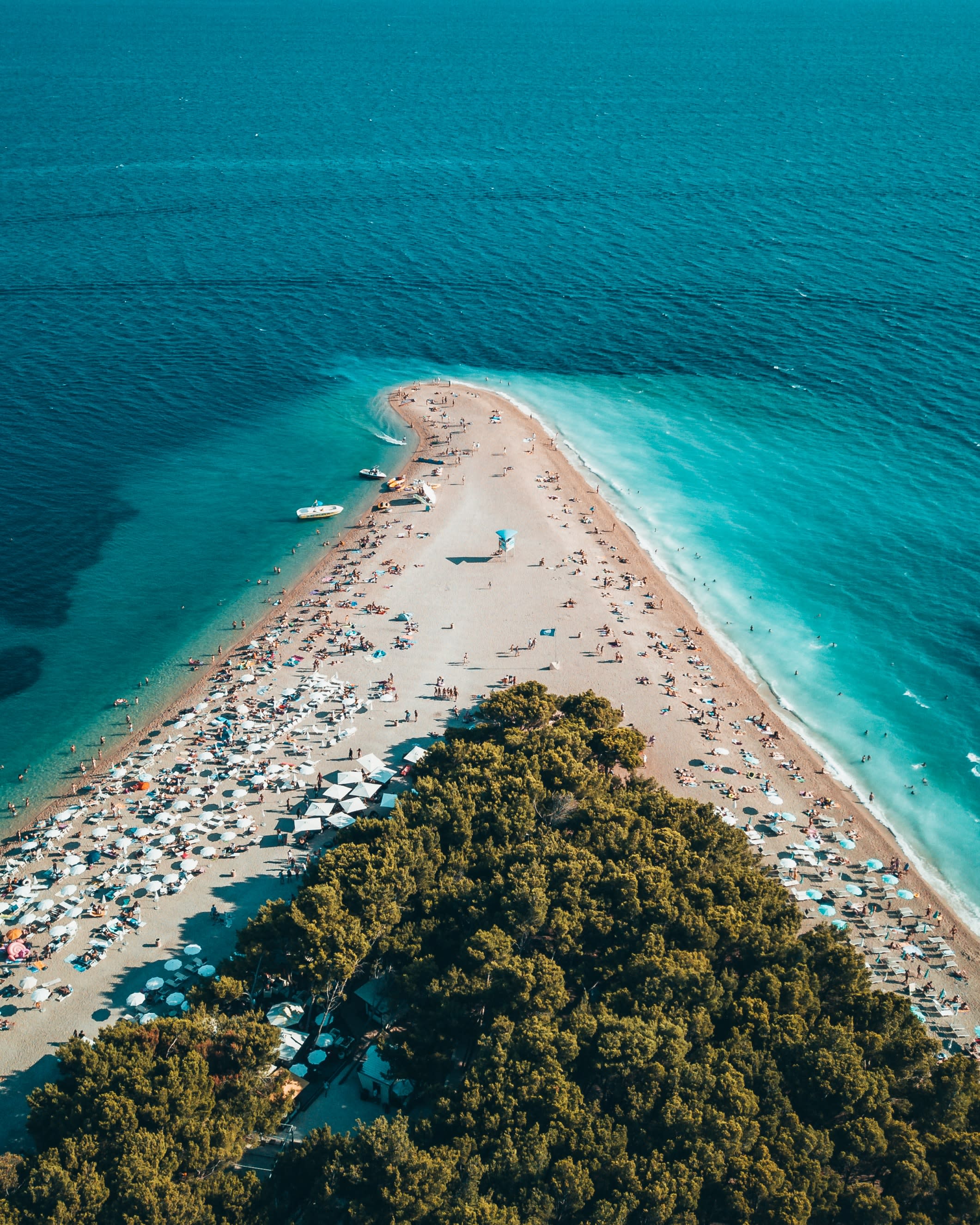 An azure sea and beach filled with people in Croatia.