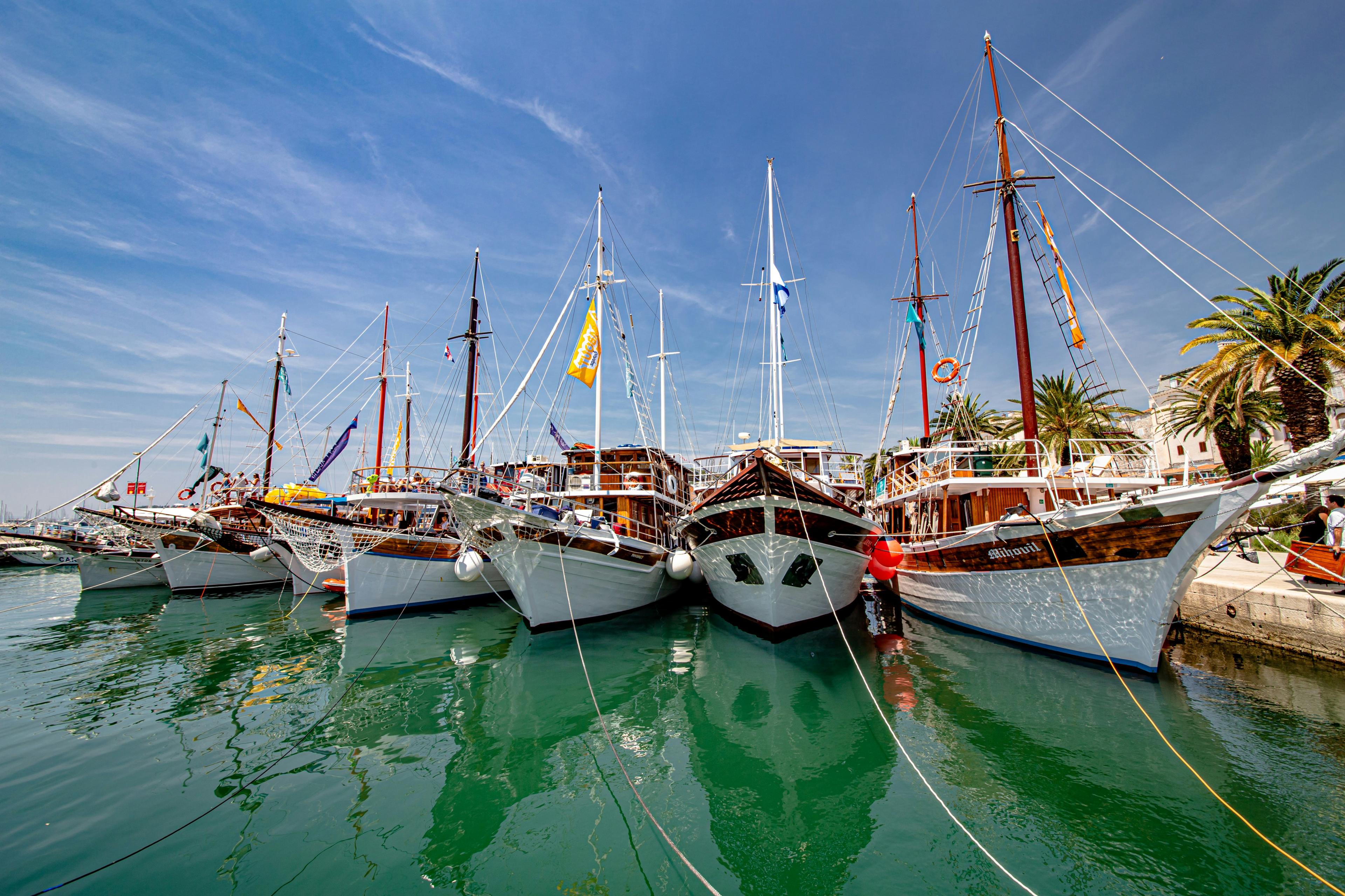 A view of Split's marina with fishing boats lined up and docked on a sunny day.