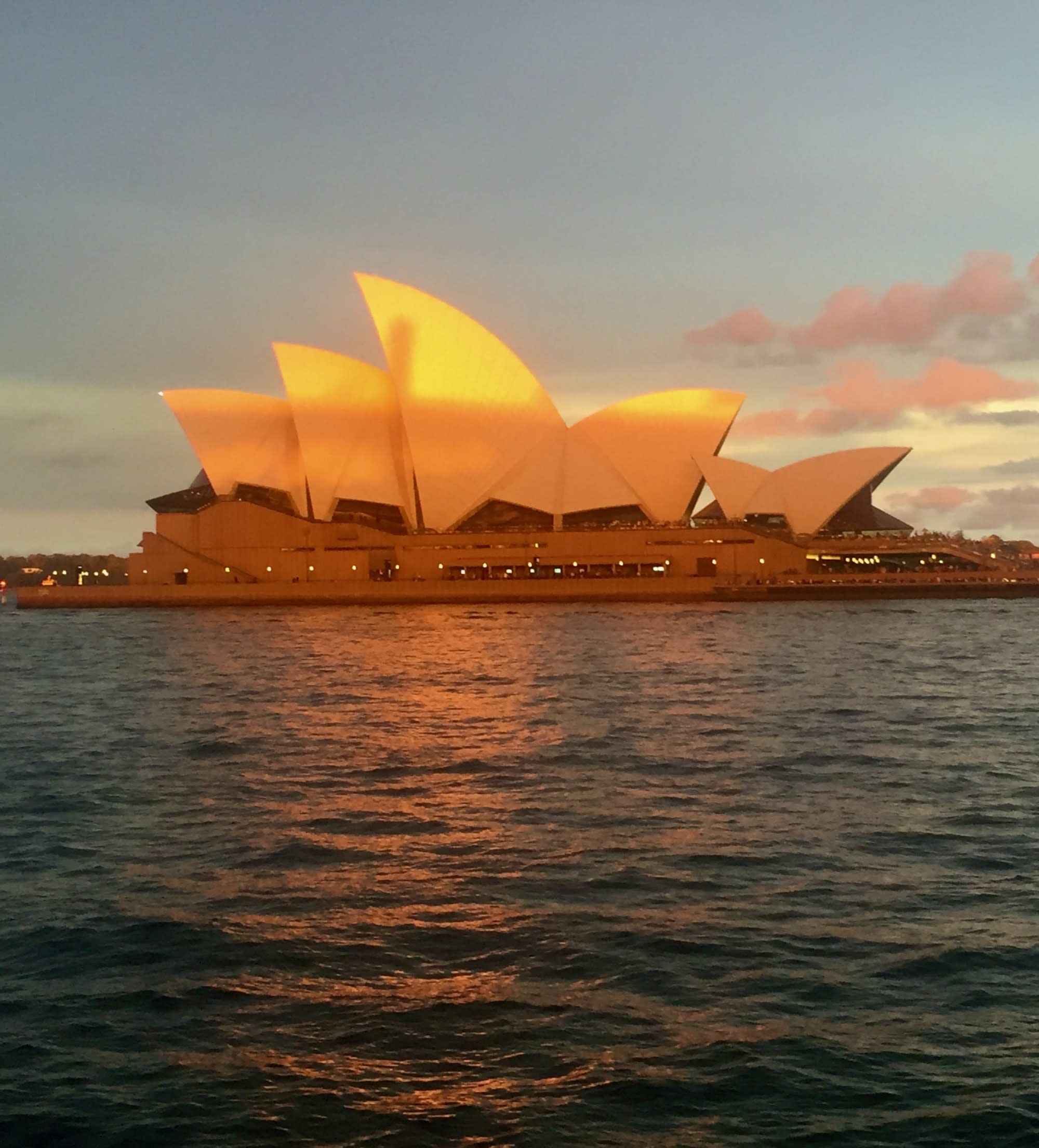 A golden sun setting over the Sydney Opera House and Harbour.