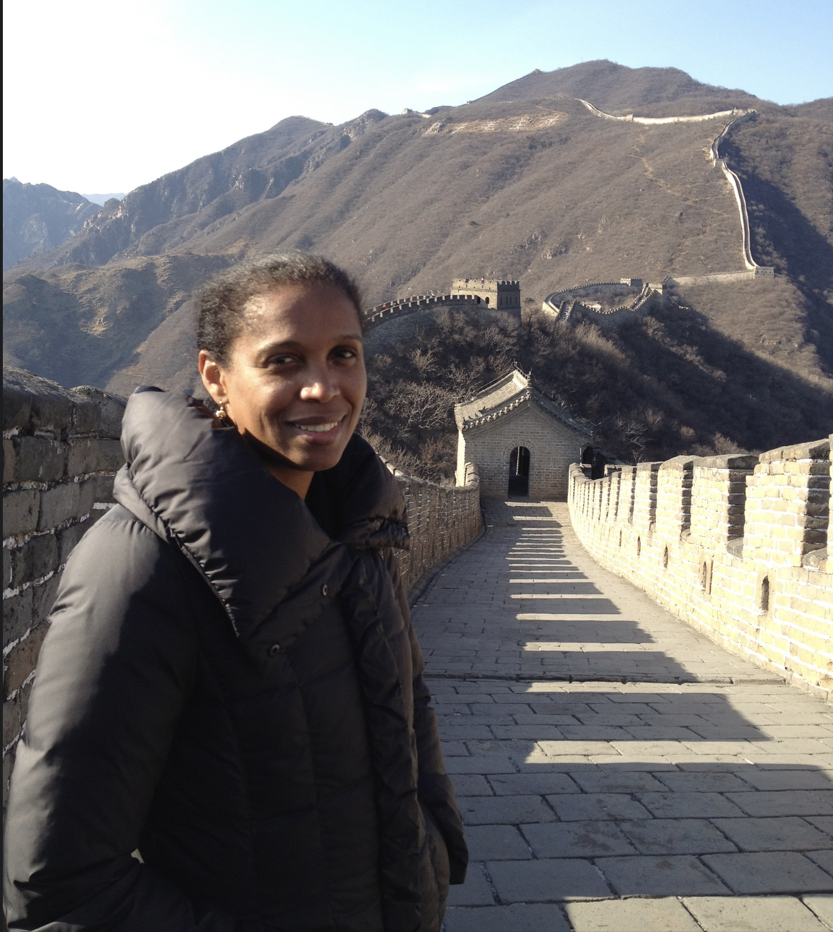A woman in front of a long wall.