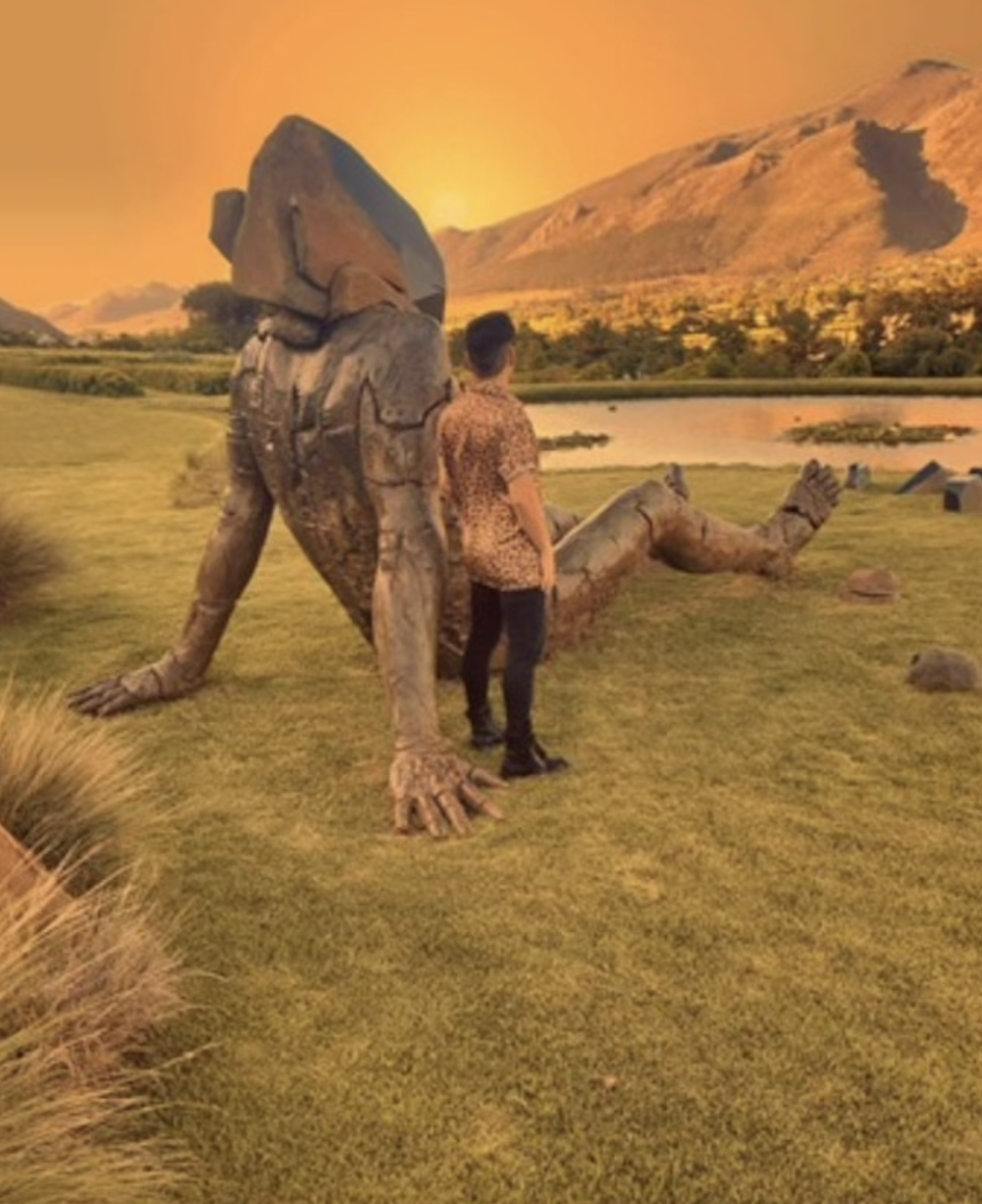 Man standing with a statue. under an orange sky