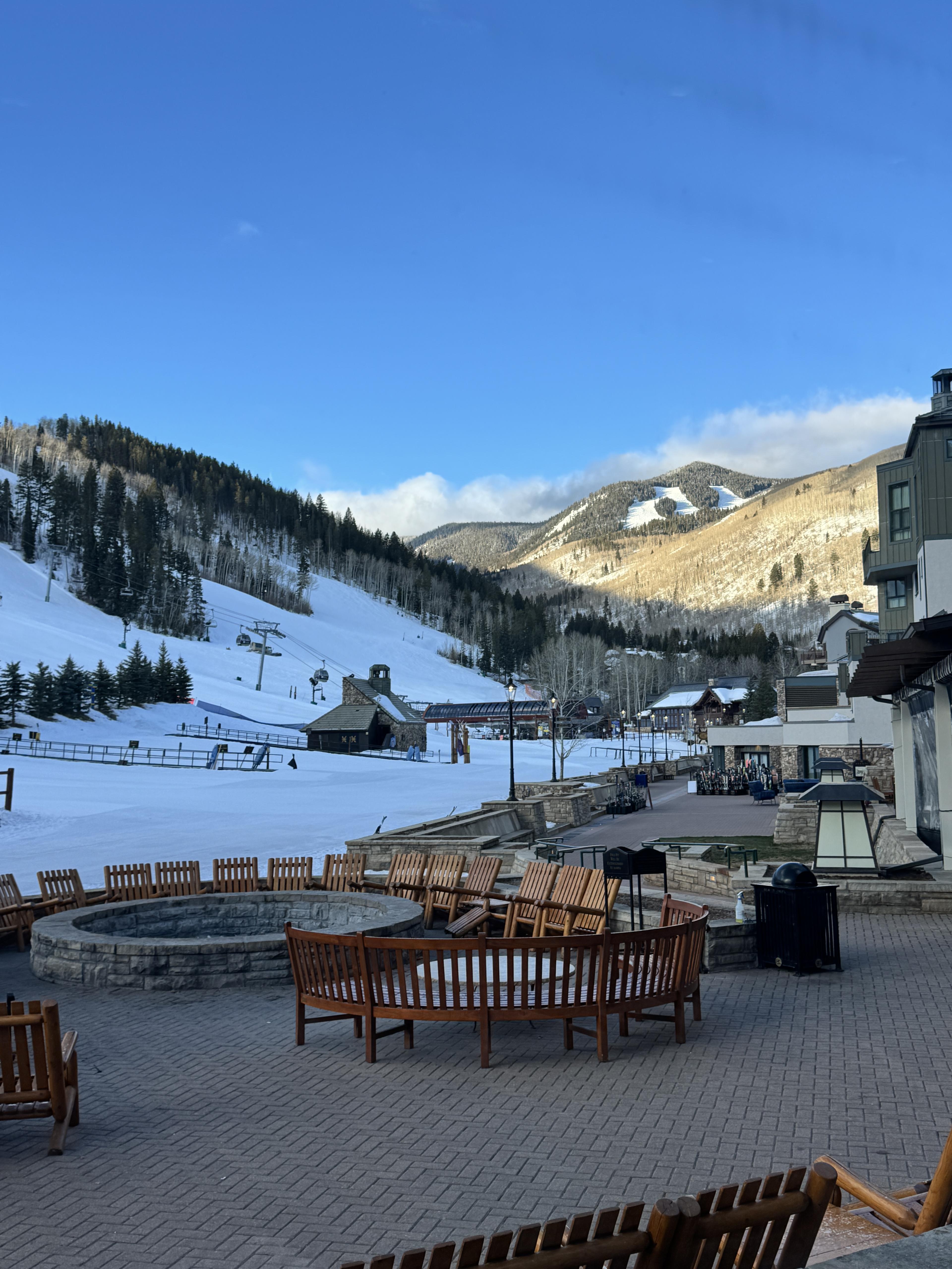 A view outside of a Colorado ski resort during the daytime, showing the venue's grand patio and snow-covered mountains.