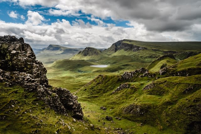 Beautiful landscape shot of green hills and white fluffy clouds in a blue sky.