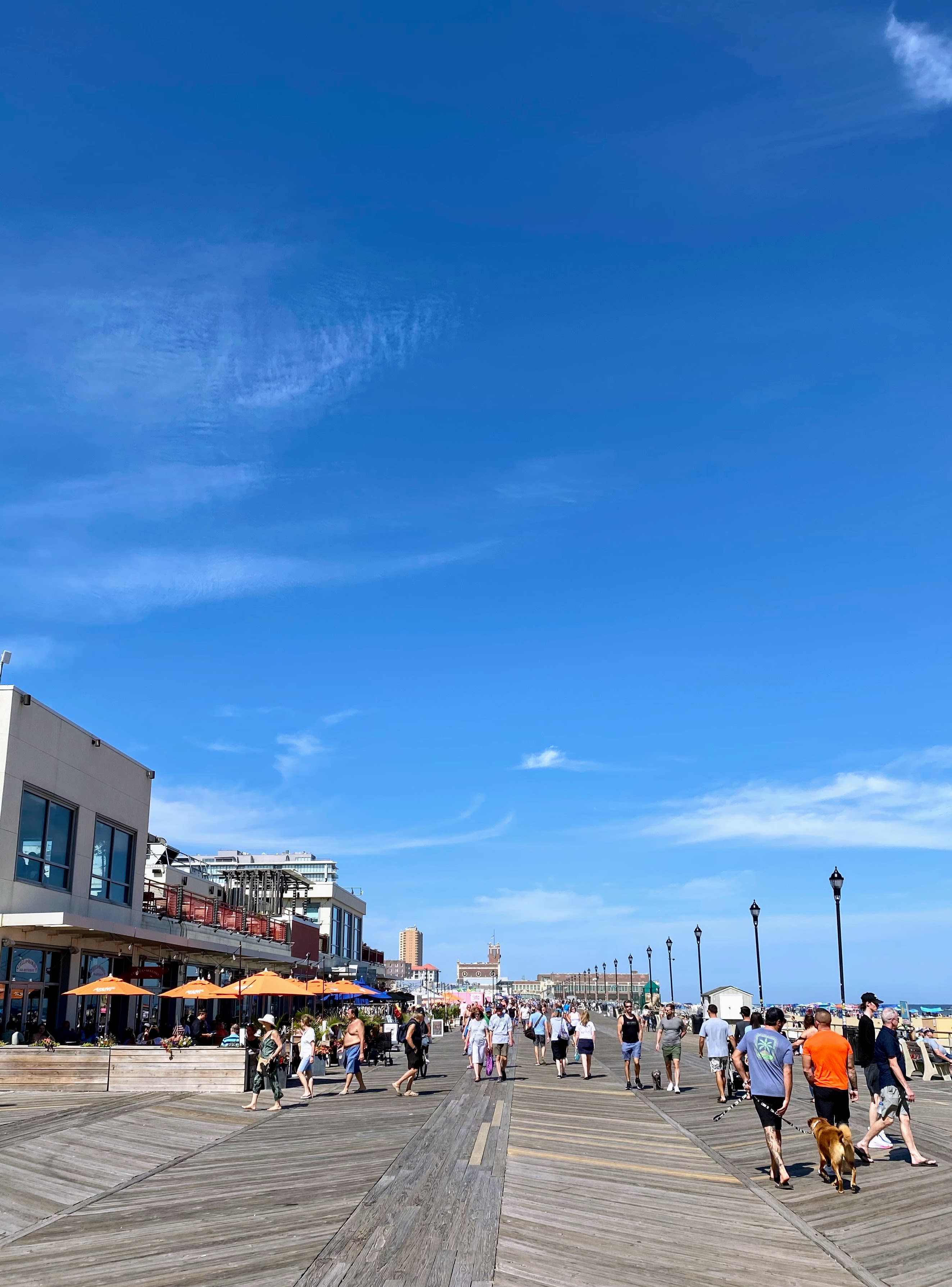 People walking along a boardwalk next to the beach during the daytime