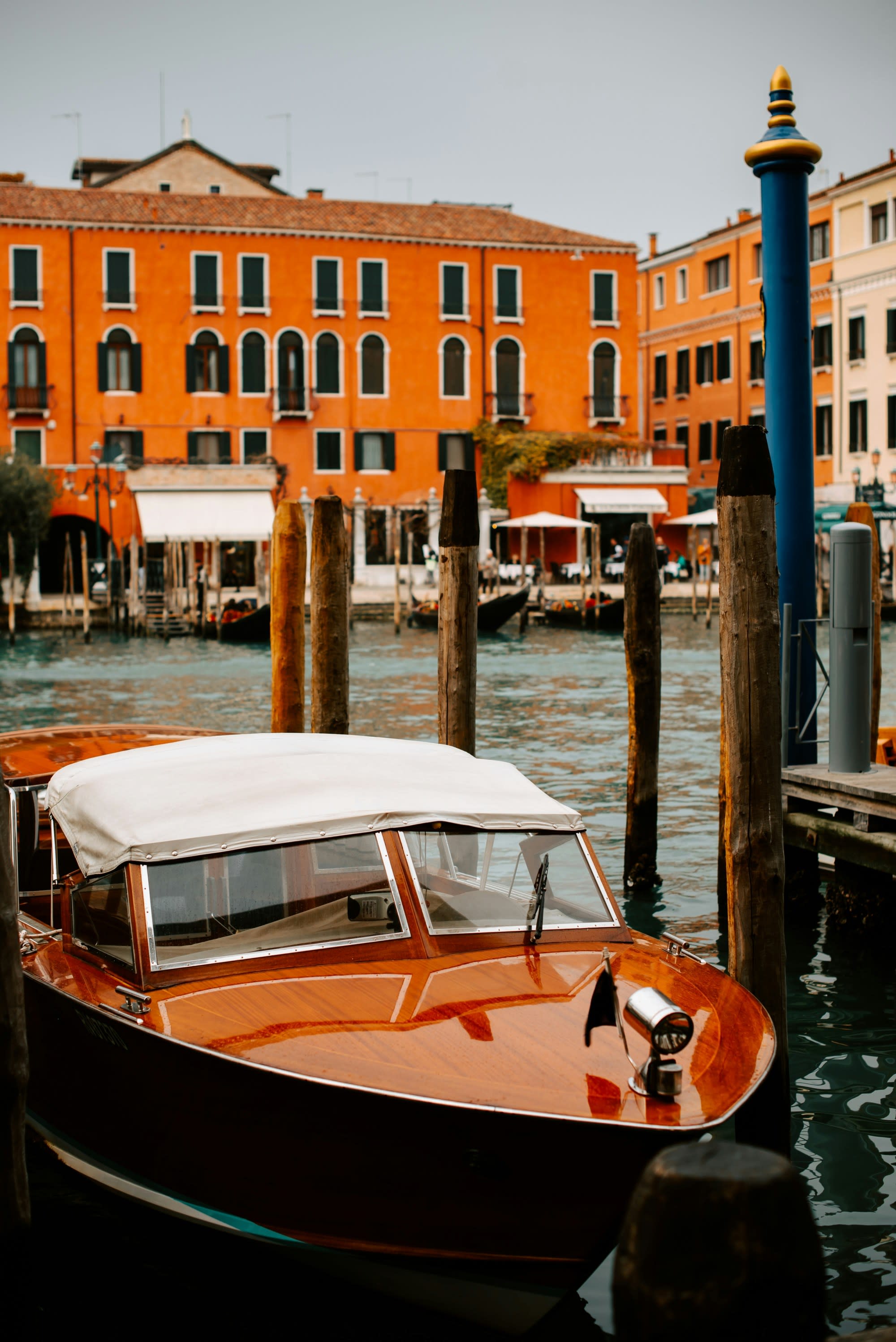 A picture of a boat parked at the dock near an orange-colored building during daytime.