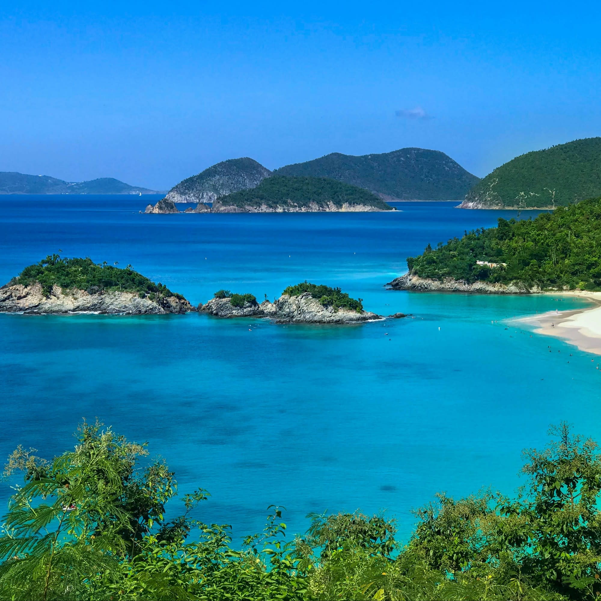 A beautiful view of bright blue water and islands covered with white rocks and trees.
