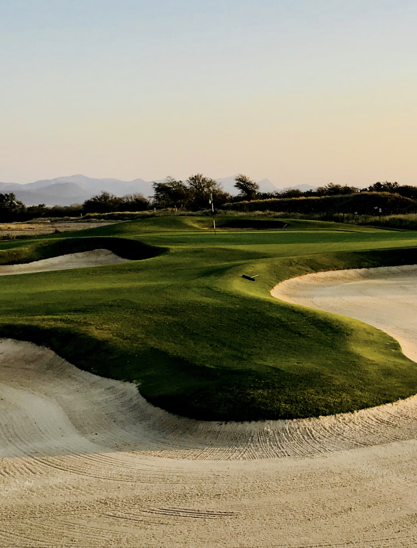 A beautiful golf course with mountains in the background.