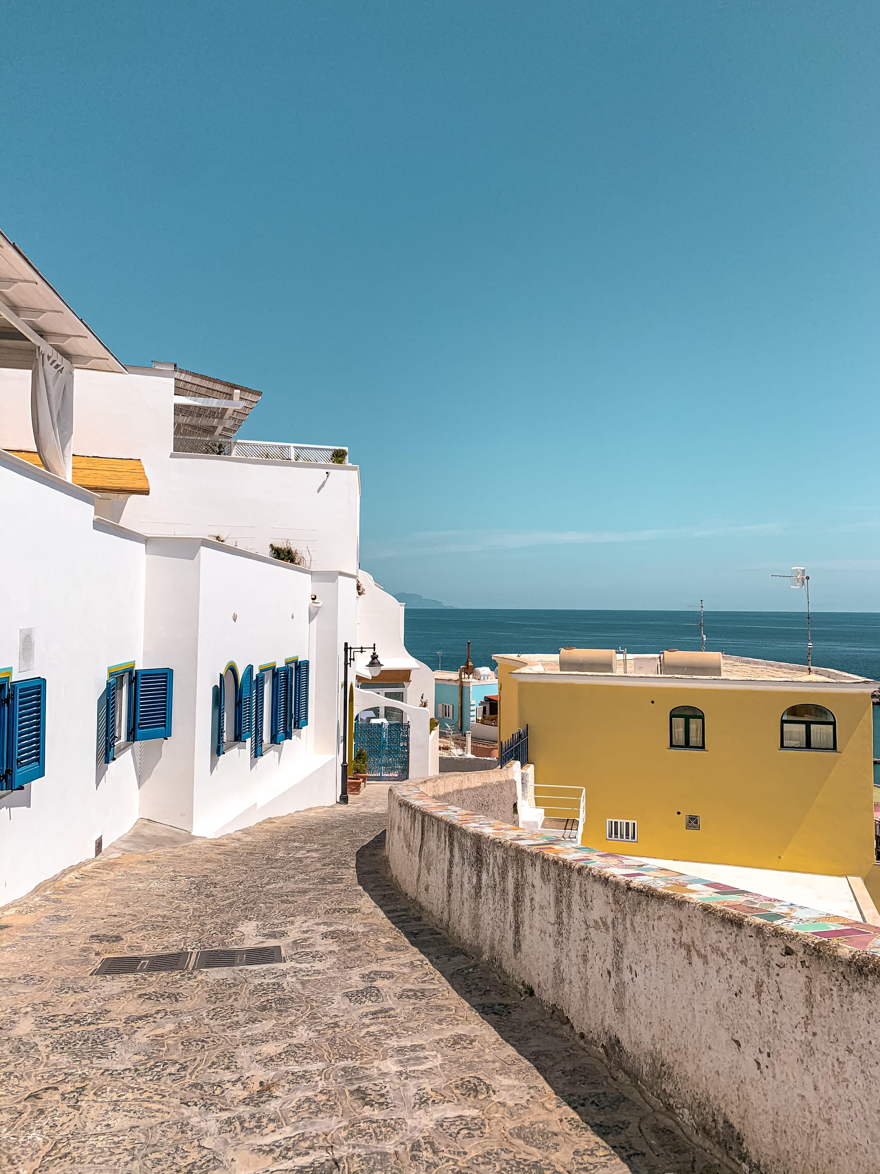 Ischia streets with whitewashed buildings and blue shutters.