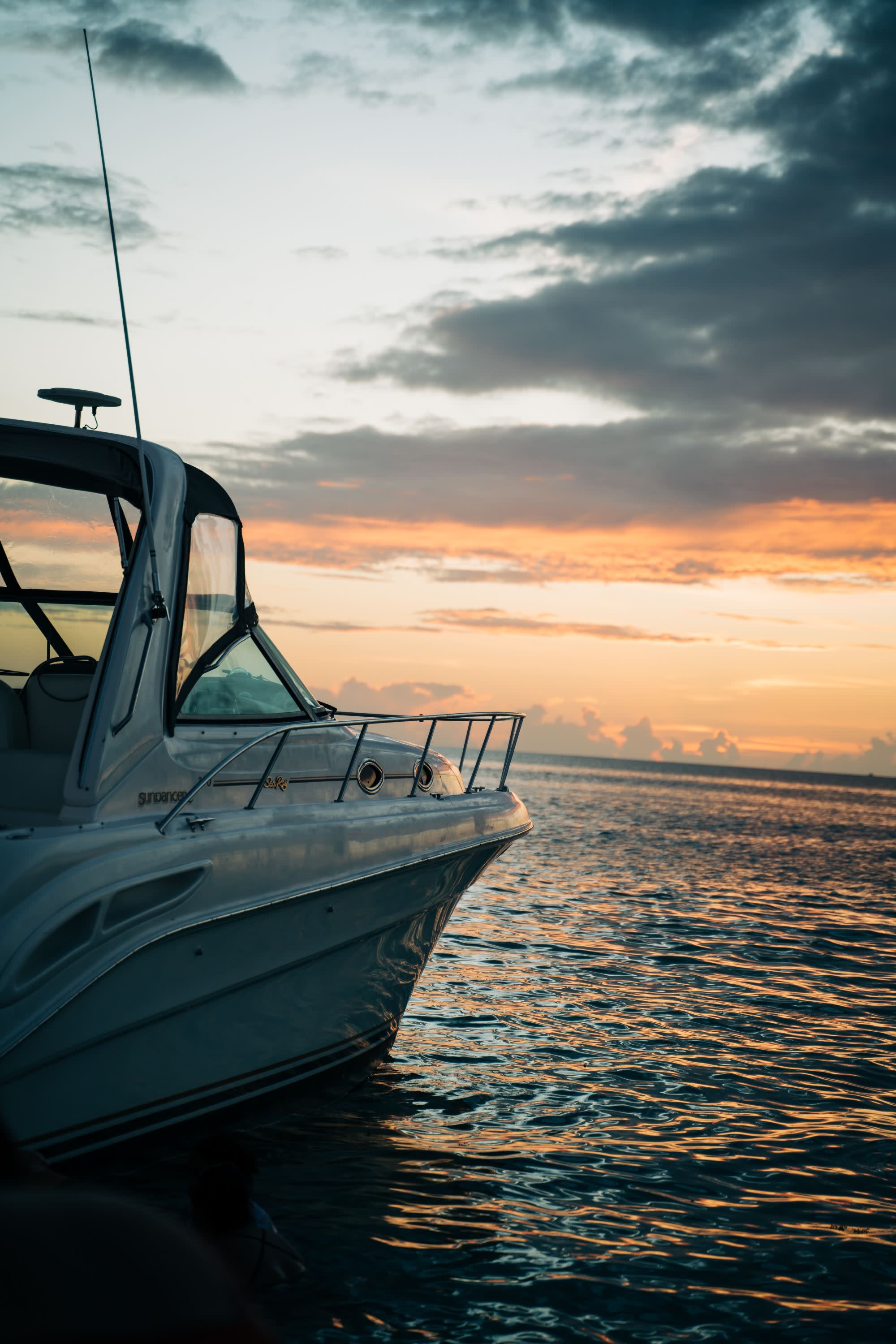 a speed boat floats on the open ocean at sunset