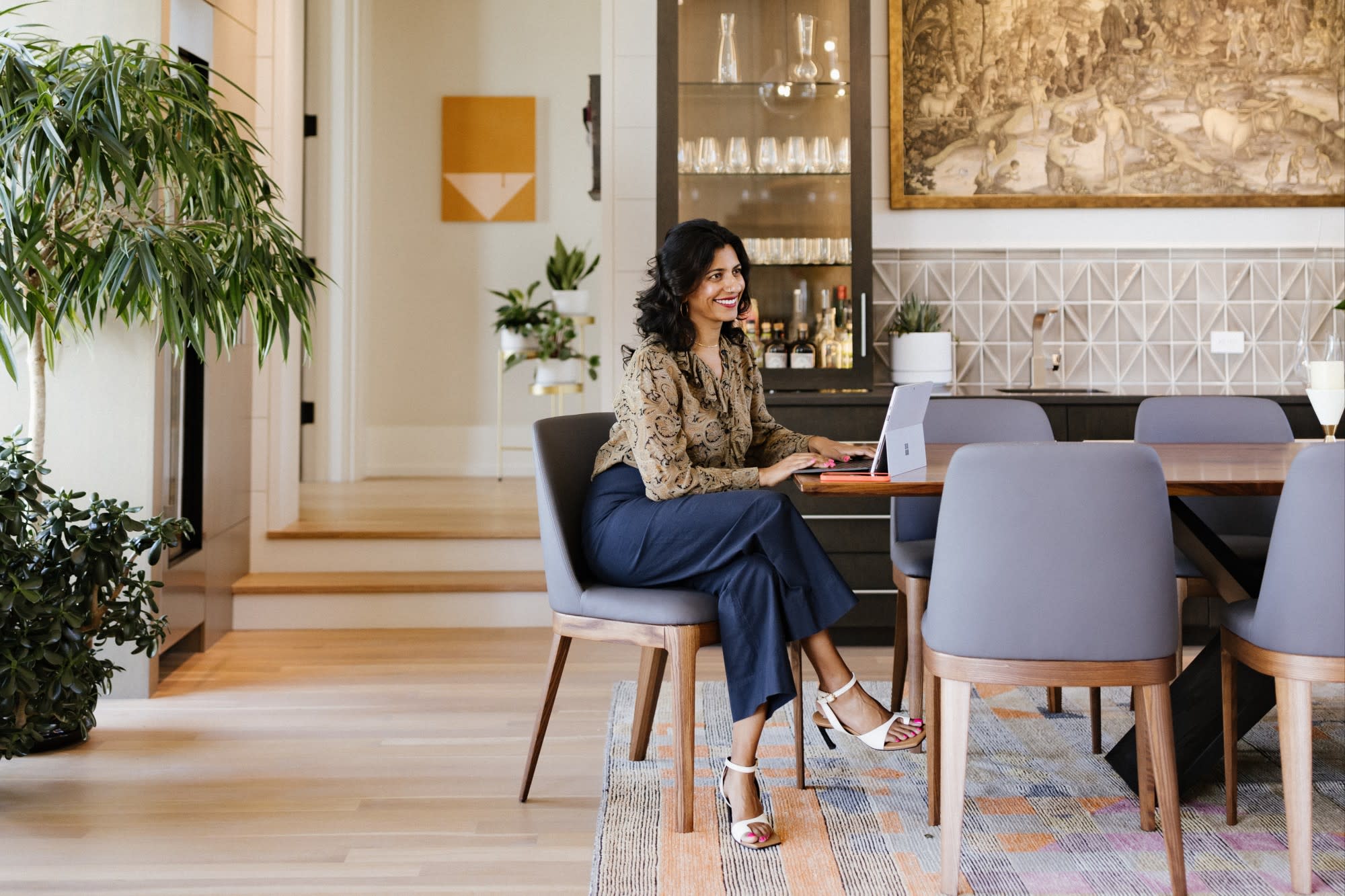 advisor Gaya Vinay sitting at a kitchen table with her laptop